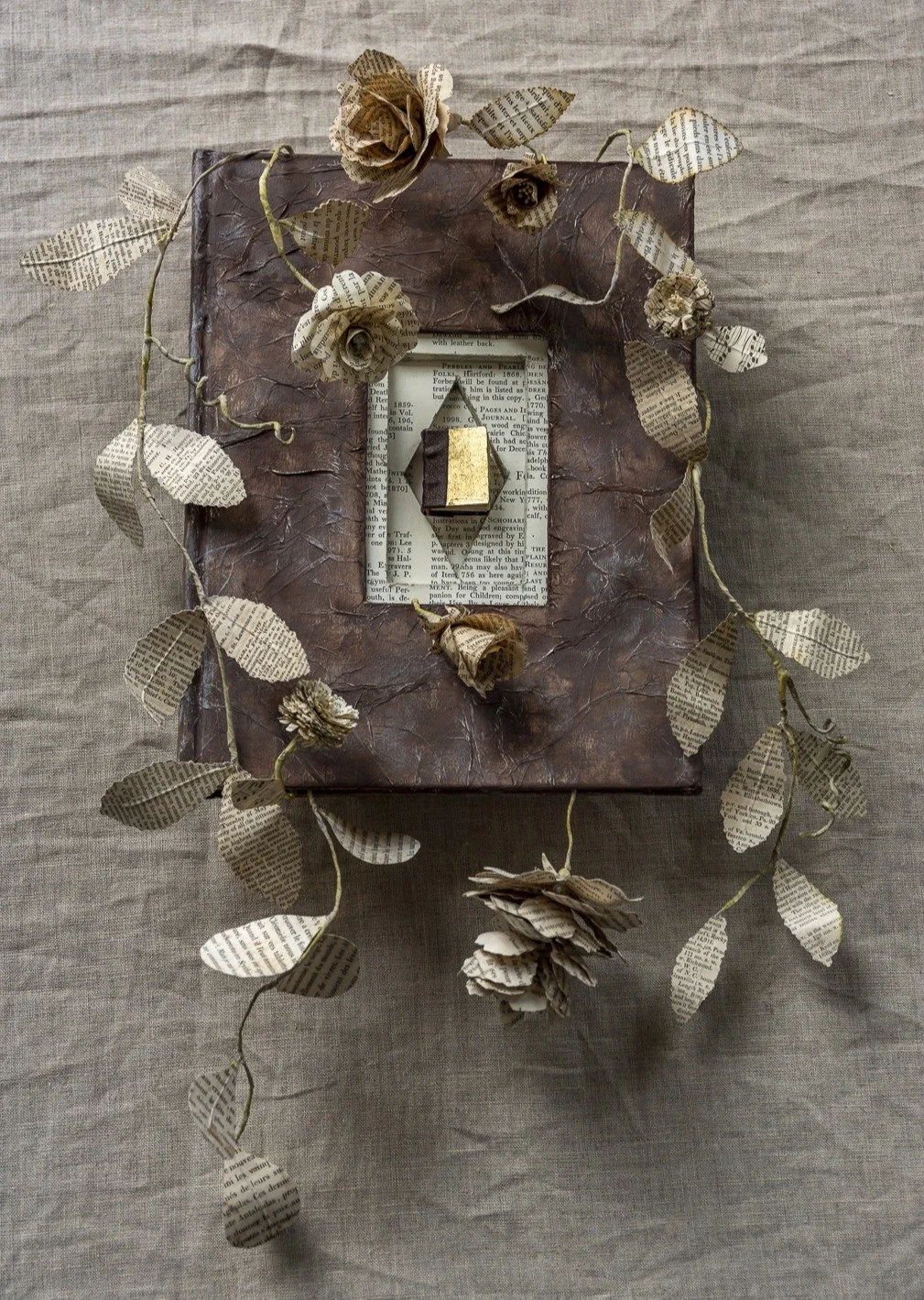 Book art sculpture with plants and flowers sculpted in paper growing out of an altered book