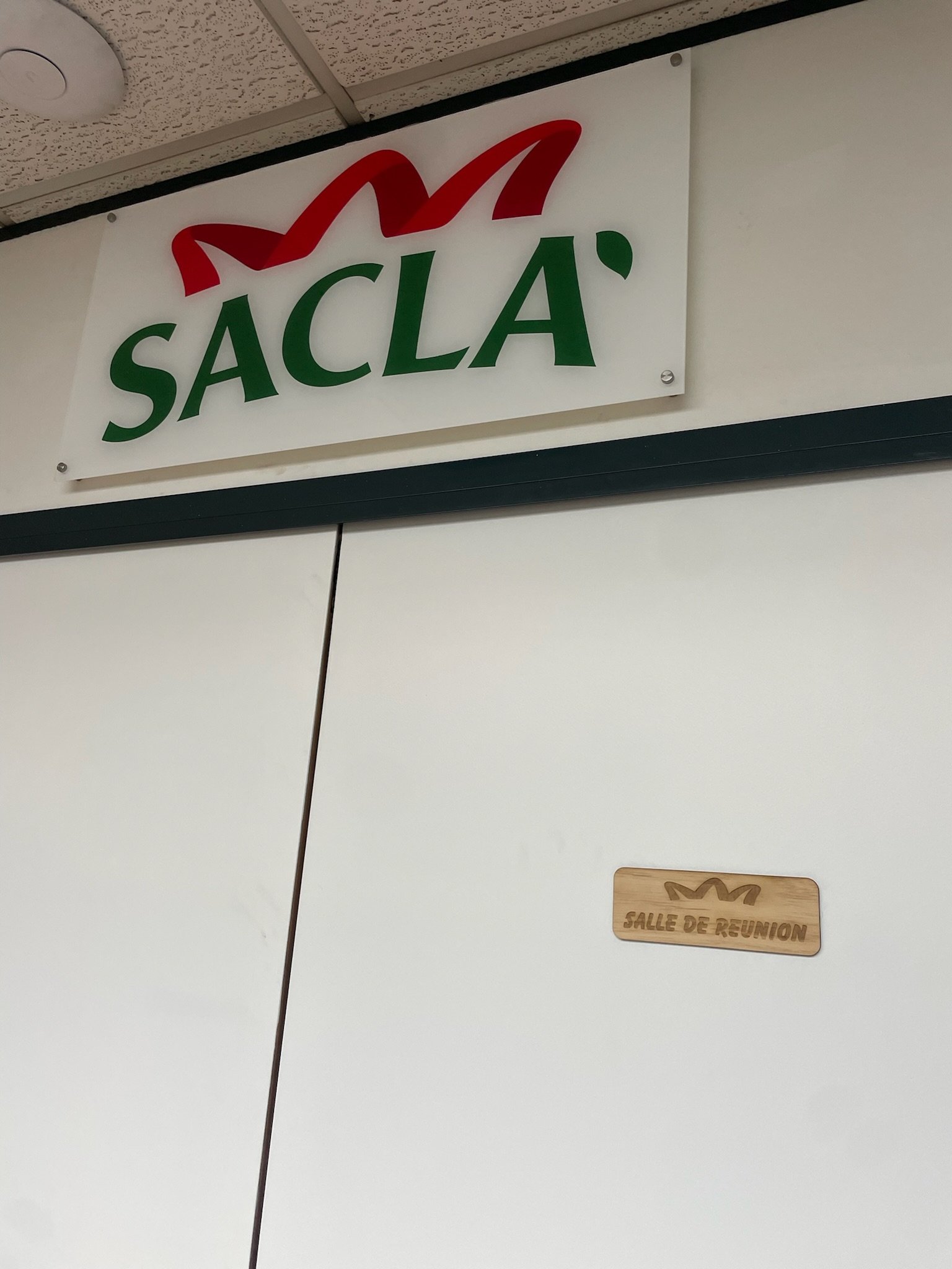 Panneau avec le logo de Sacla, une marque italienne, et une petite plaque en bois indiquant la salle de réunion.