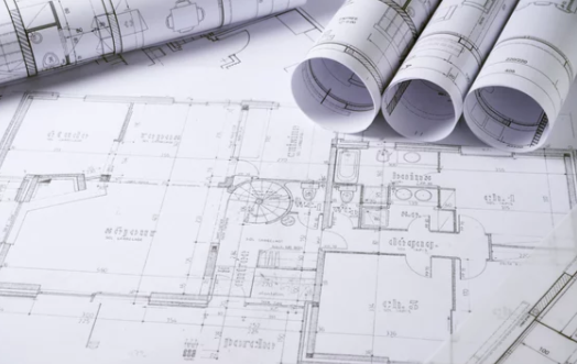 Architectural blueprints and rolled-up design plans on a table.