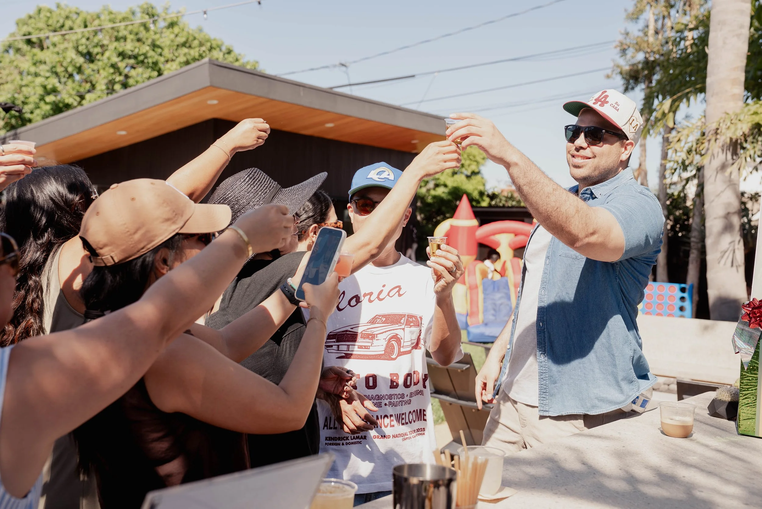 People celebrating outdoors, raising drinks in a toast at a party or gathering.