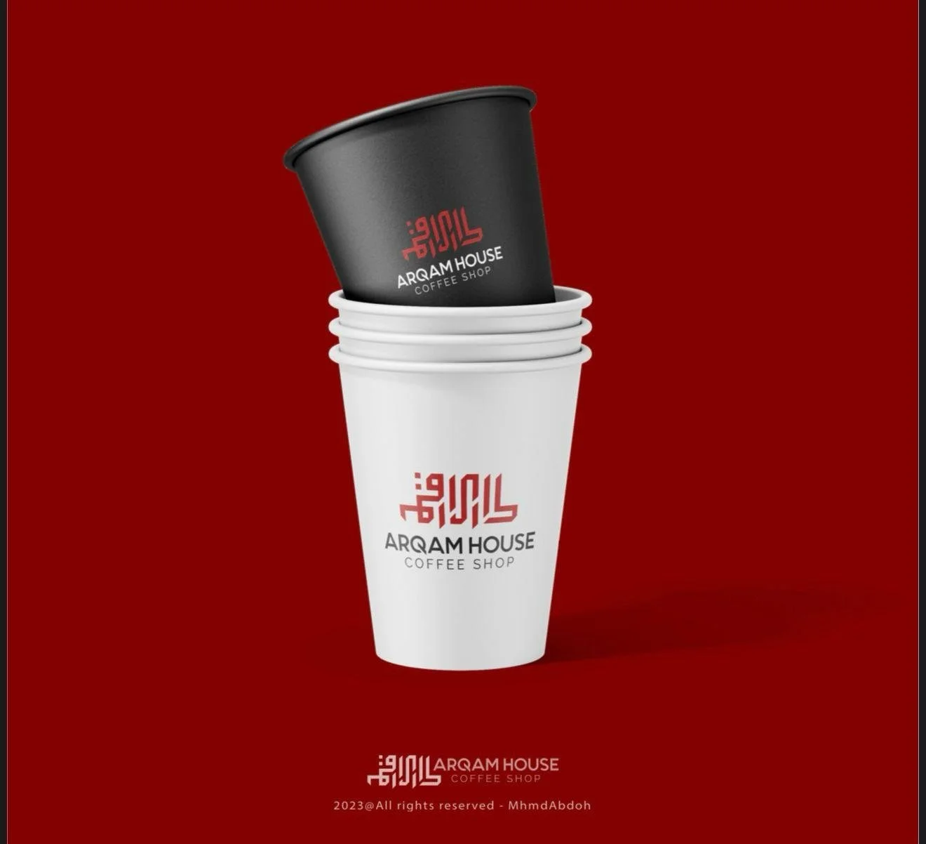 Stack of white and black coffee cups with 'Arqam House Coffee Shop' branding against a red background.