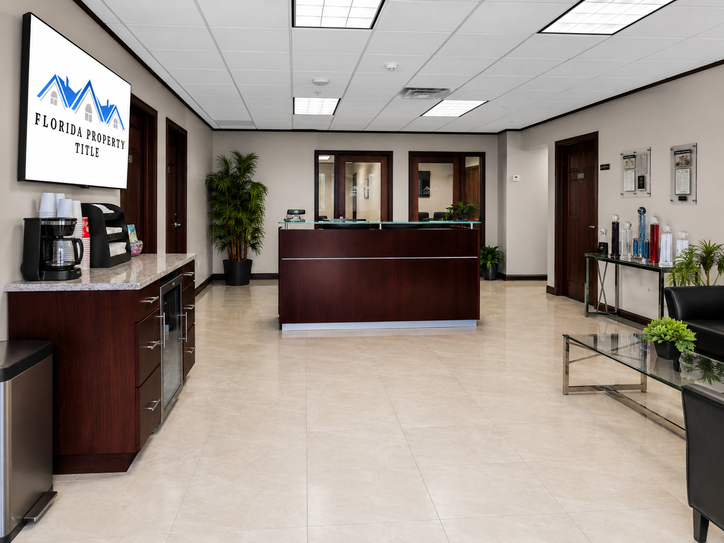 Florida Property Title Estero reception area with beverage center, seating area, and awards display in a professional real estate closing office
