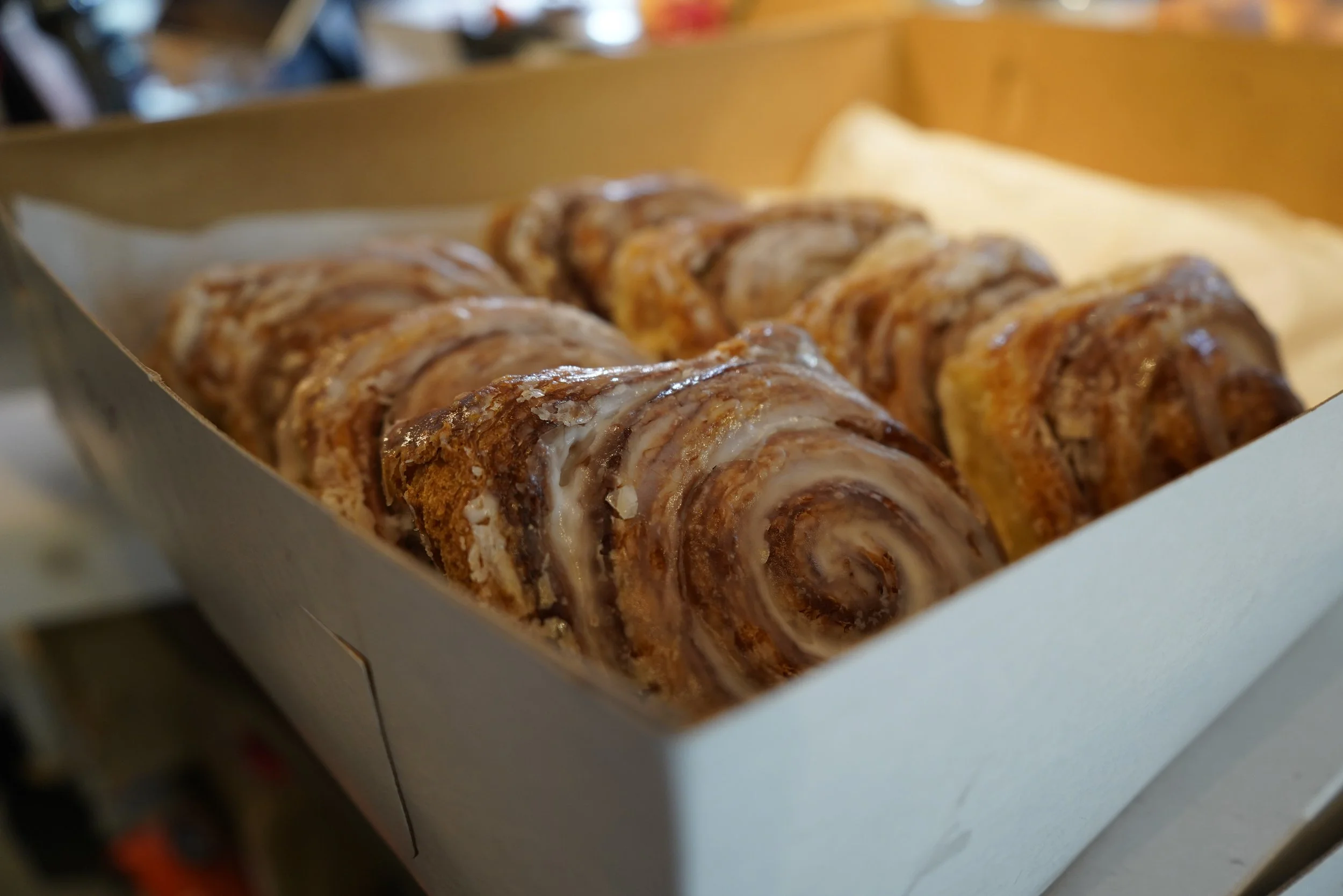 Cinnamon rolls with icing in a white box.