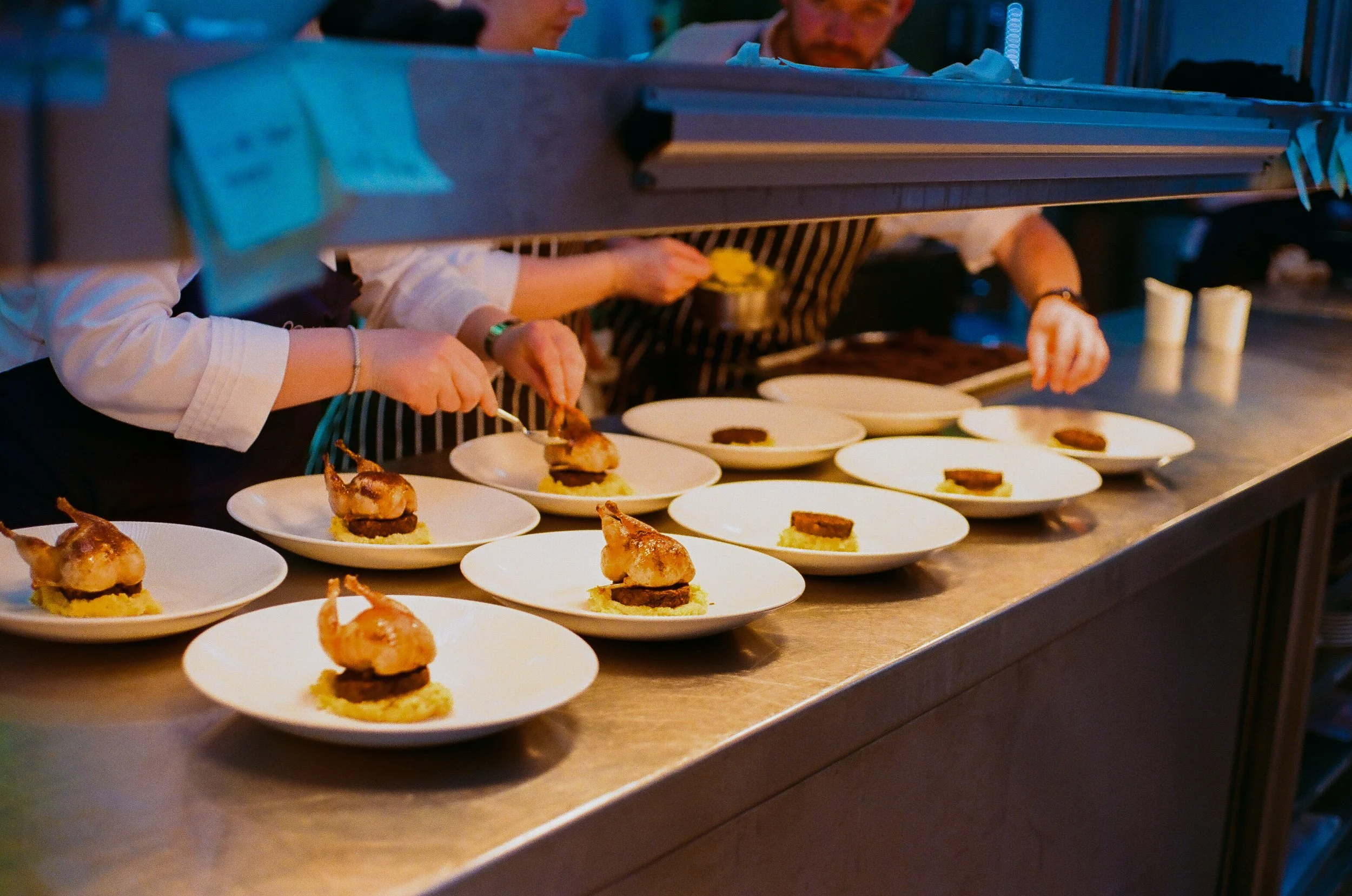 People preparing and plating gourmet dishes in a professional kitchen.