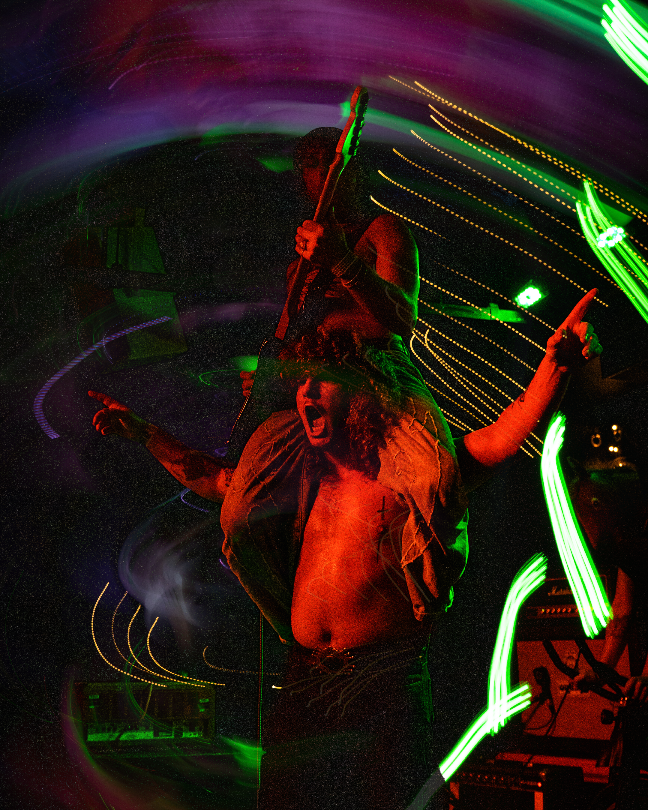 A performer holding a microphone on stage with colorful light trails and streaks moving around, creating a dynamic and energetic atmosphere.