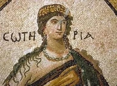 Close-up of a Byzantine mosaic depicting a woman with dark hair, dressed in traditional attire, with text that says "Soteria" in ancient Greek in the background.
