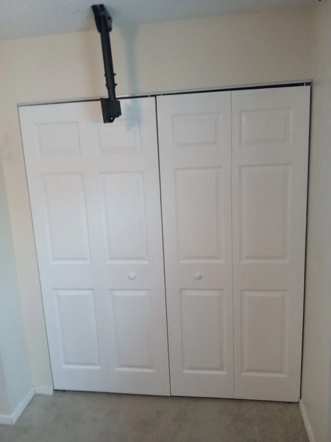A white closet with sliding doors and a black sliding door track installed above it.