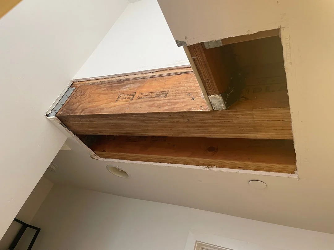 Ceiling with a large hole exposing wooden beams and drywall.