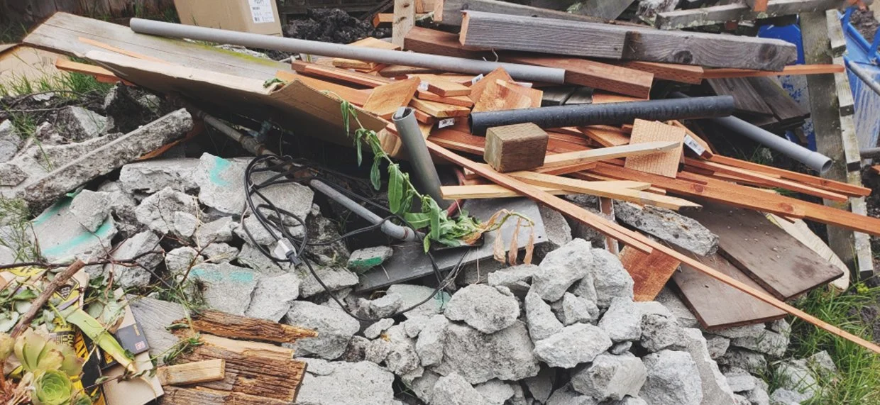A pile of construction debris including rocks, broken wood, pipes, and miscellaneous trash.