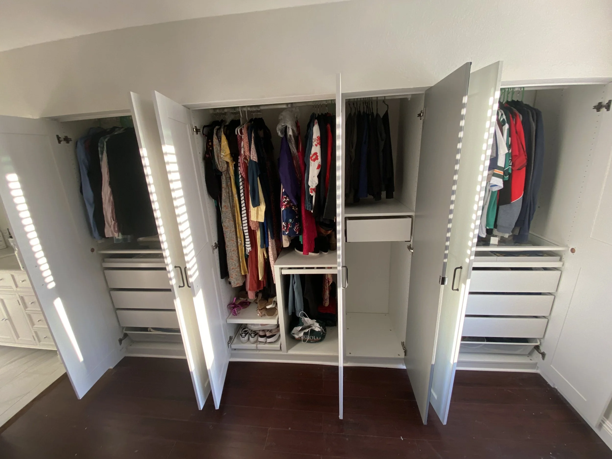 Open closet with hanging clothes, shoes, and drawers.