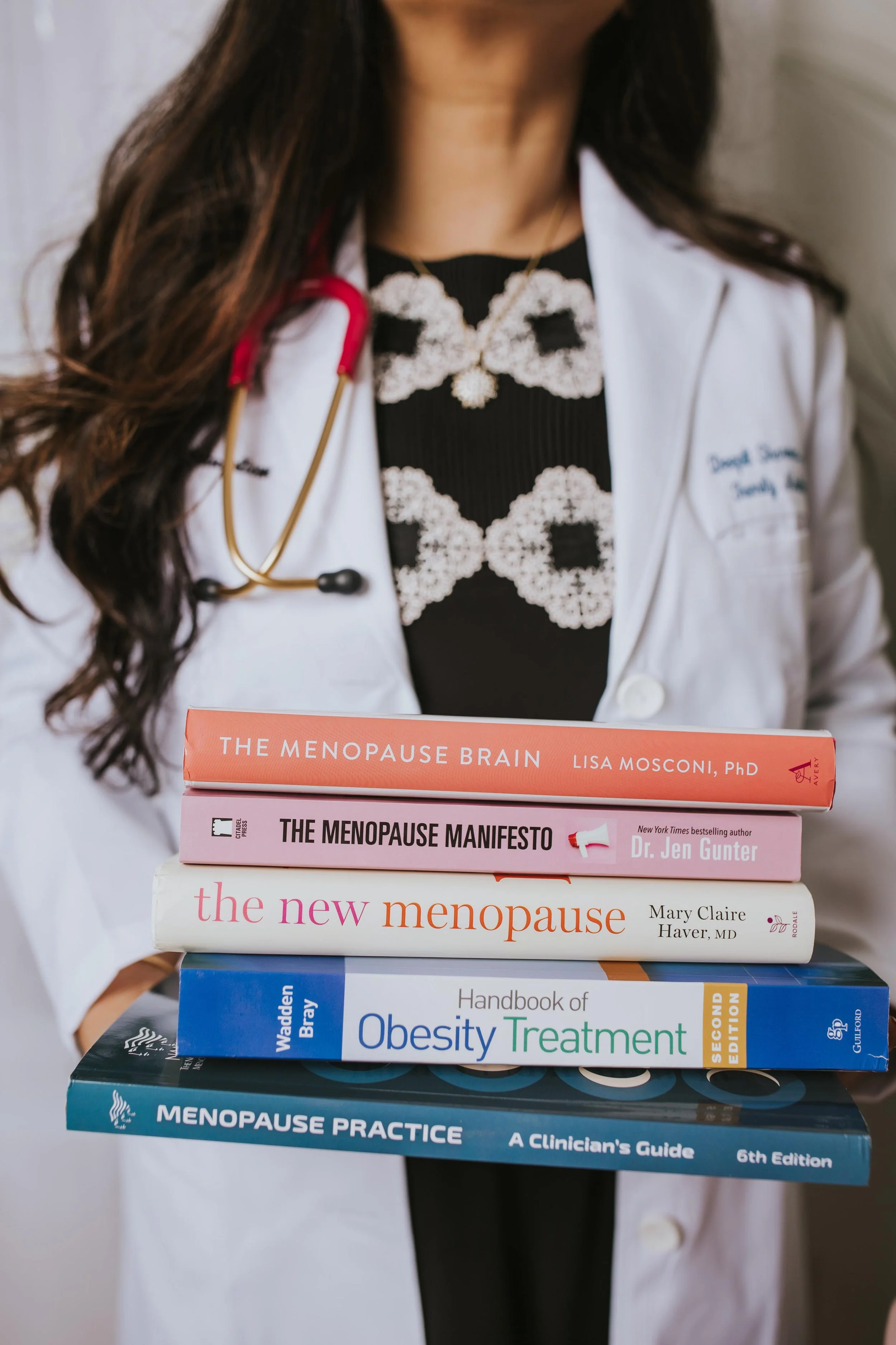 Dr. Sharma holding a stack of books on menopause and obesity