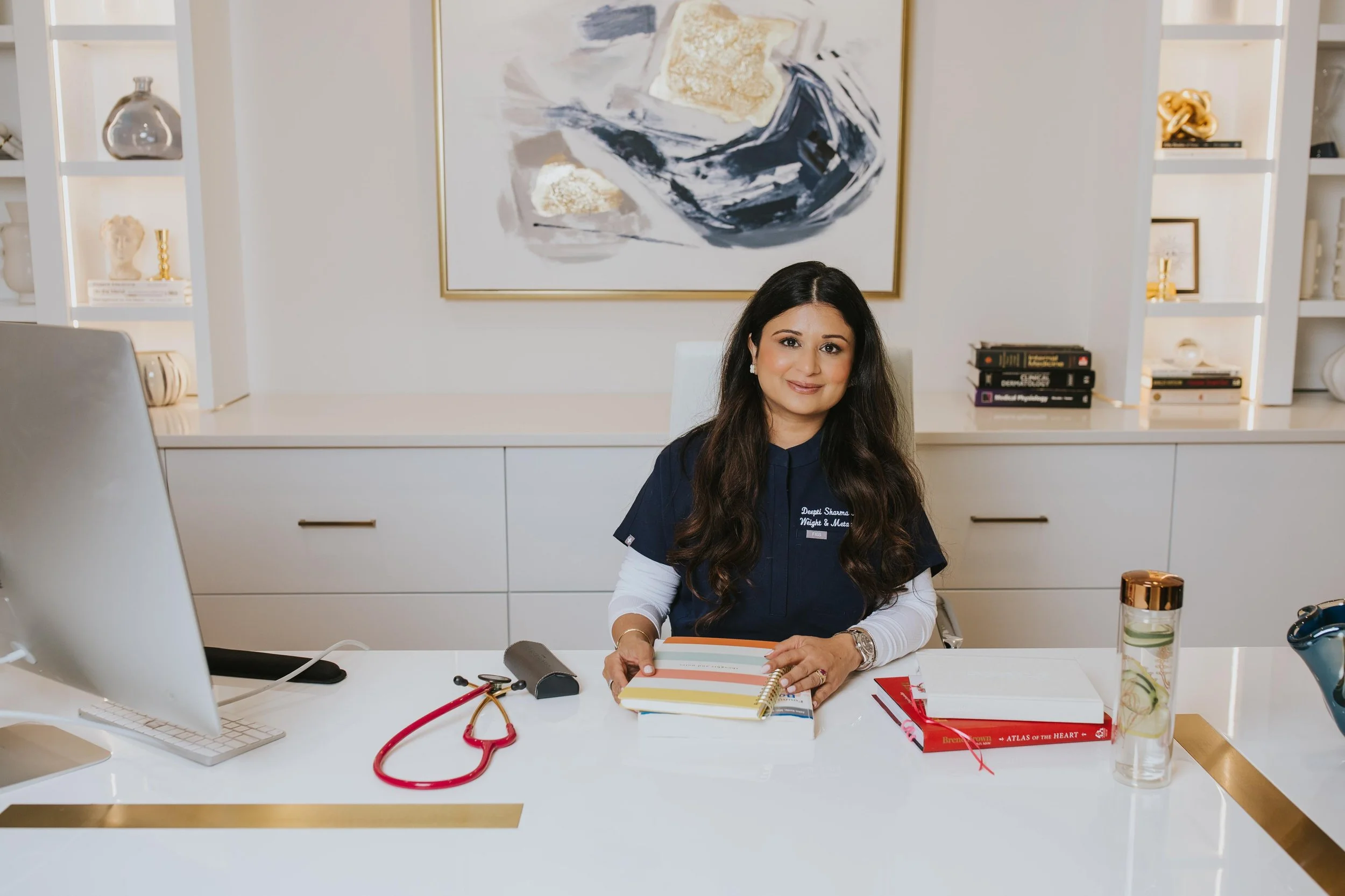 Dr. Sharma smiling at her desk in her office