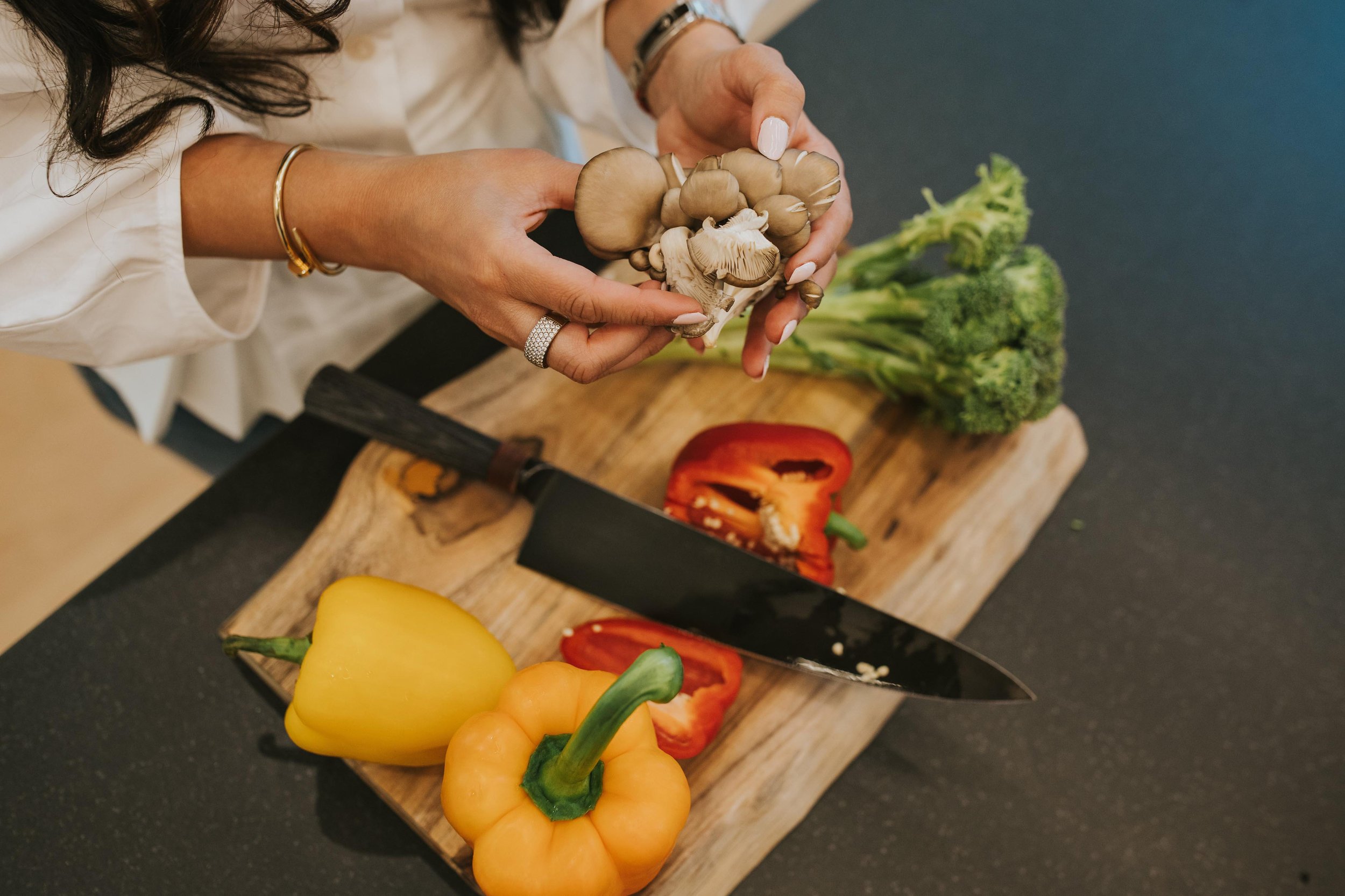 closeup of Dr. Sharma holding mushrooms over cutting board with veggies
