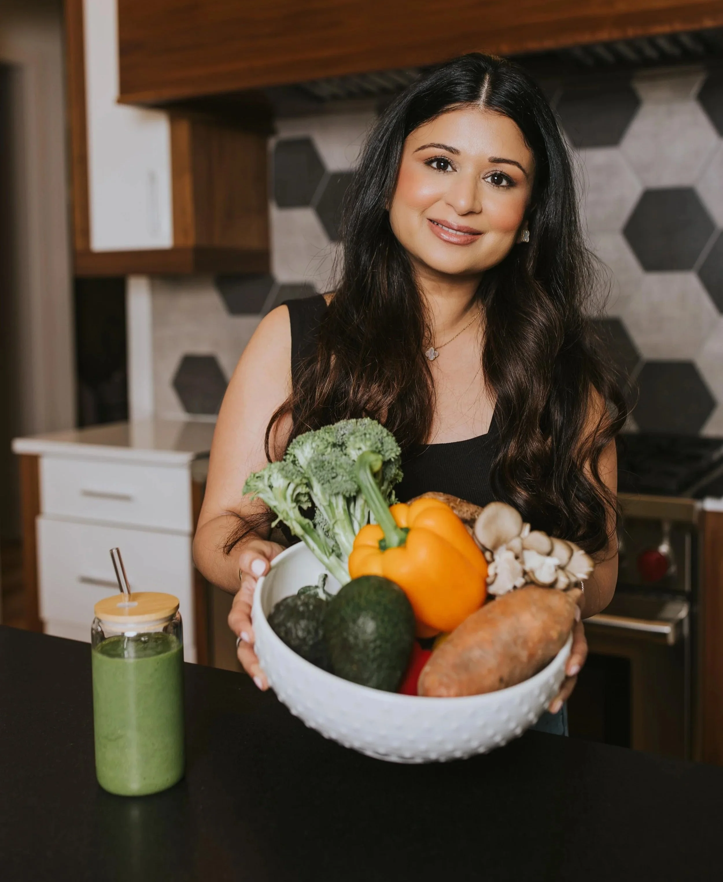 Dr. Sharma holding a bowl of veggies in her kitchen
