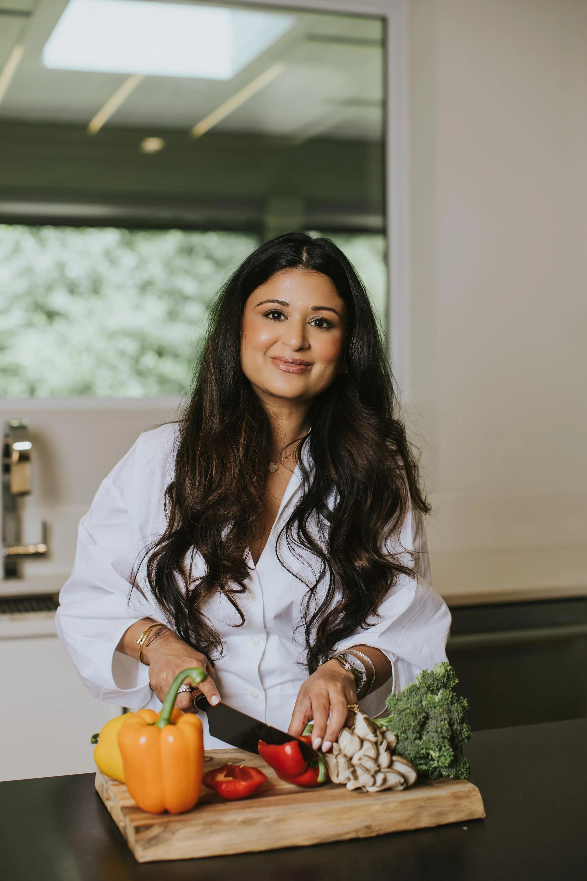 Dr. Deepti Sharma smiling while cutting vegetables in her kitchen