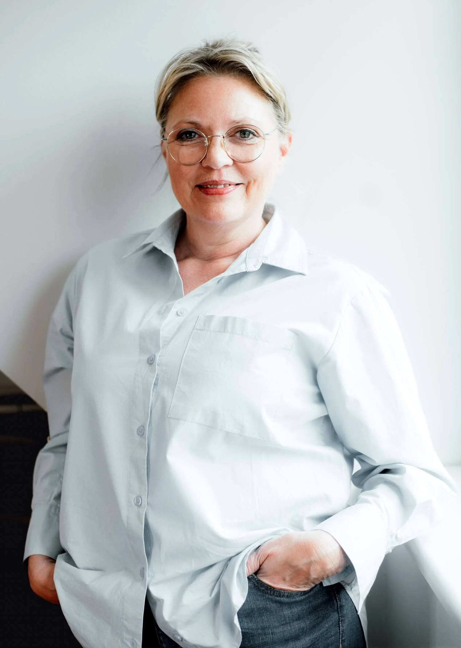 Porträt von Melanie Friedrich. Sie trägt eine helle Bluse und eine runde Brille und lächelt freundlich in die Kamera.