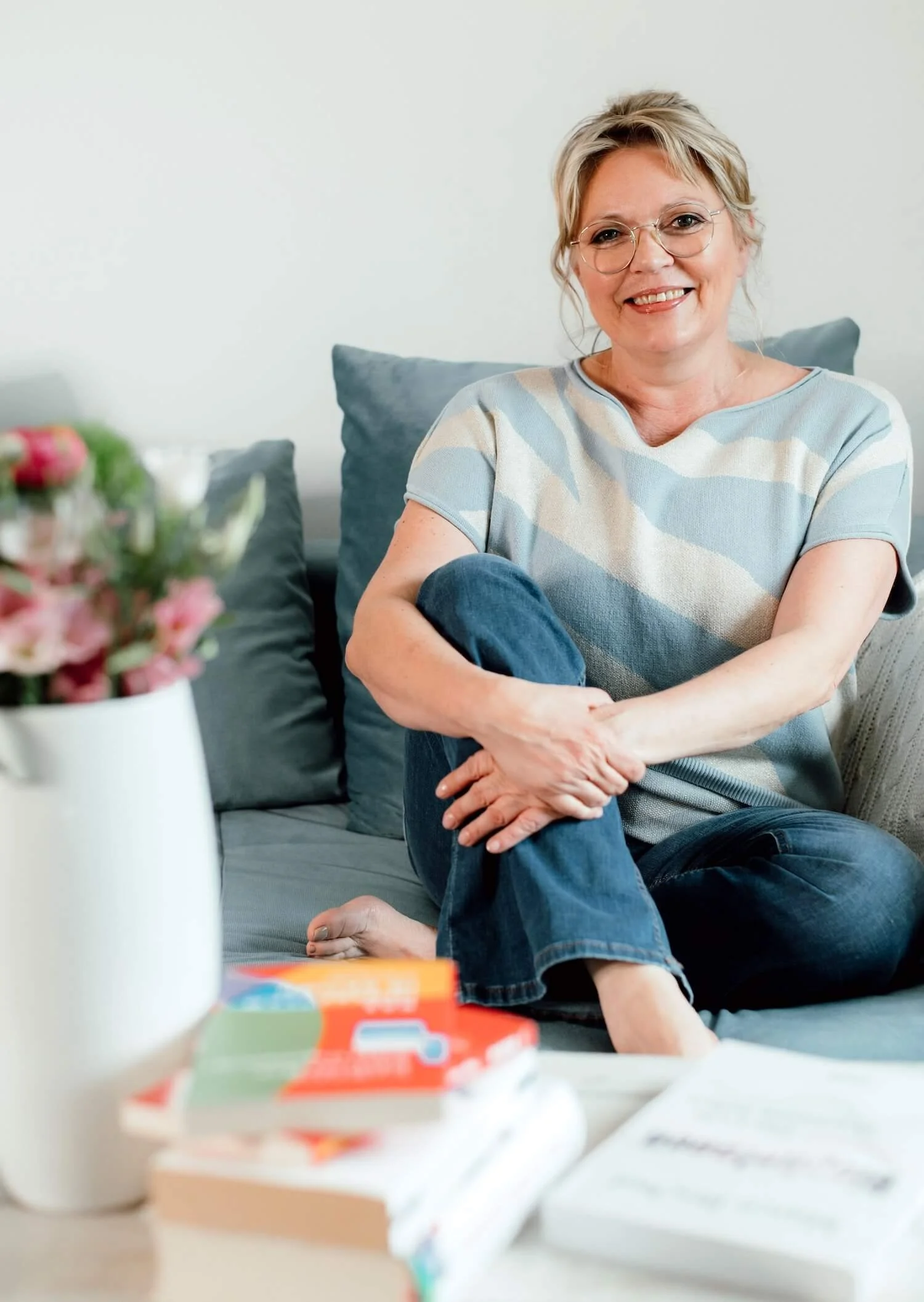 Porträt von Melanie Friedrich auf einem Sofa in heller, freundlicher Umgebung.