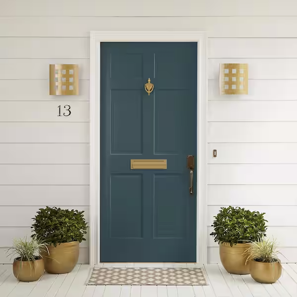 Front door painted dark blue with a mail slot, door knocker, and handle, flanked by two wall-mounted lanterns, with house number 13 and potted plants on both sides.