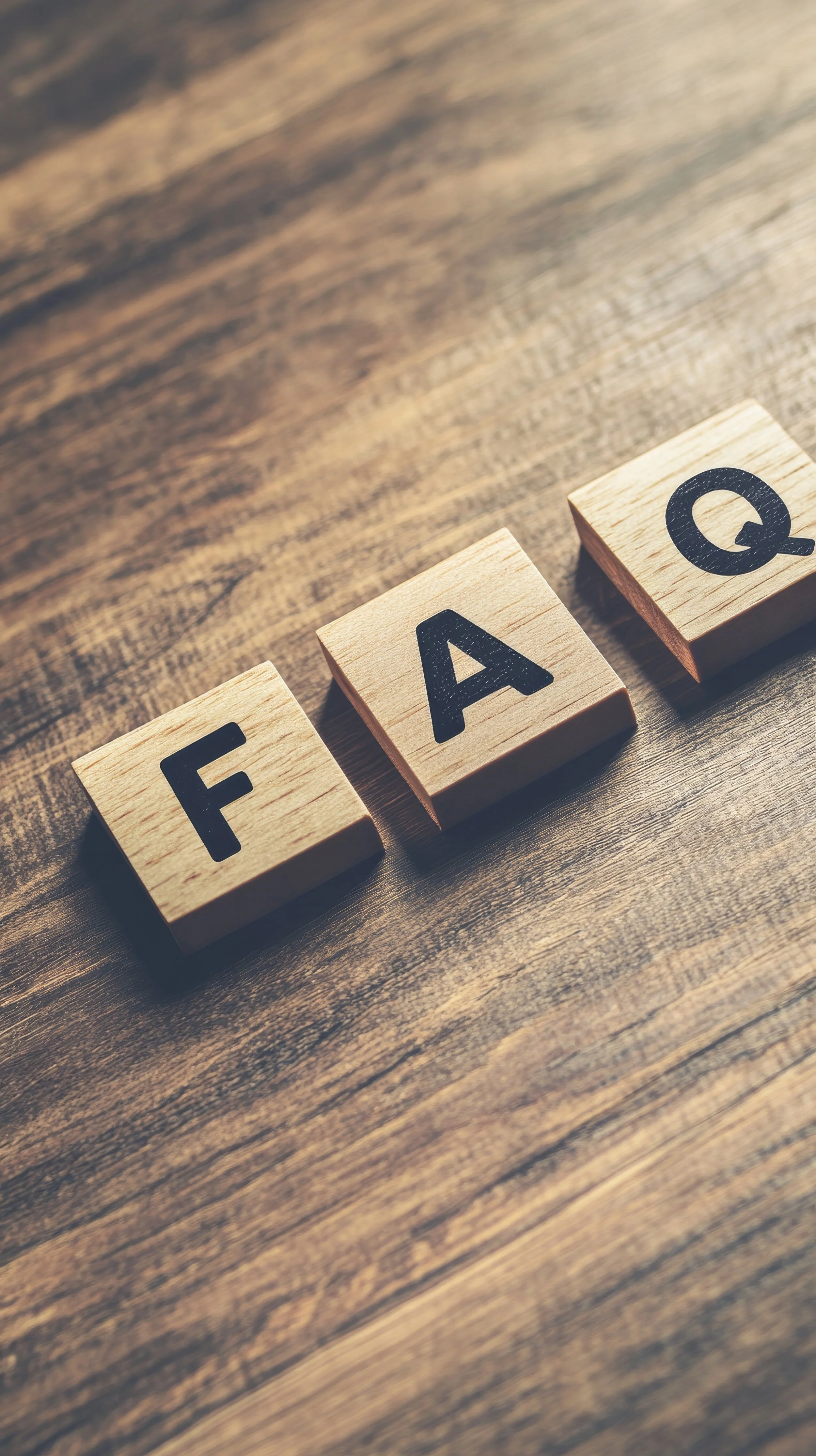 Wooden blocks spelling 'FAQ' on a wooden surface.