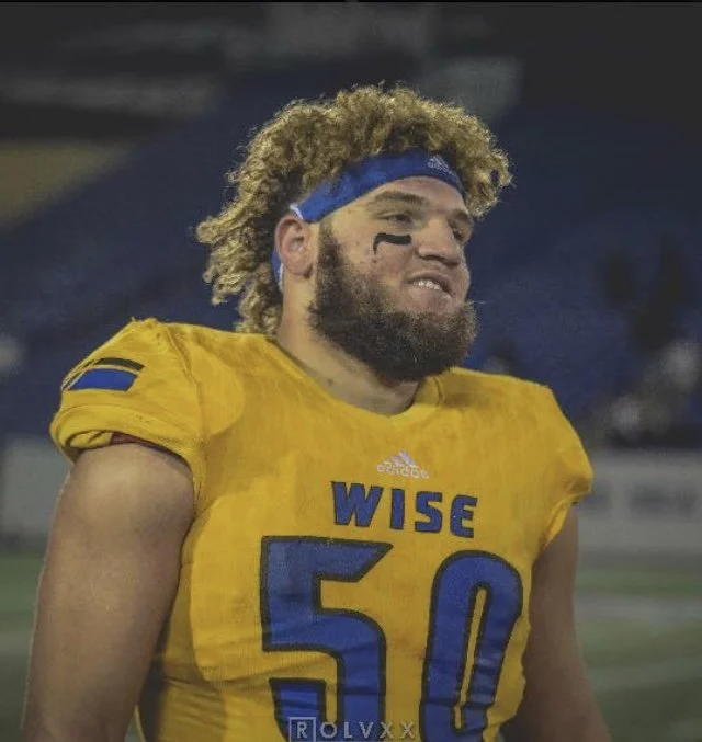 A football player in a yellow jersey with the number 50 and the word WISE on the front, wearing a blue headband, with a beard and black face paint, standing on a football field.