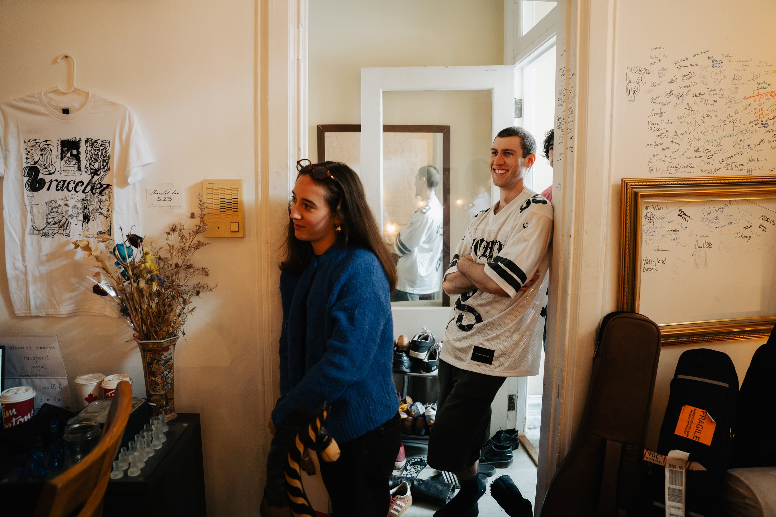 Sofia Dawson, host of The Extended Plays smiling and engaging in a musical performance taking place on set. Items such as a shirt with a design and handwritten notes on the wall are visible, creating a warm and casual atmosphere.