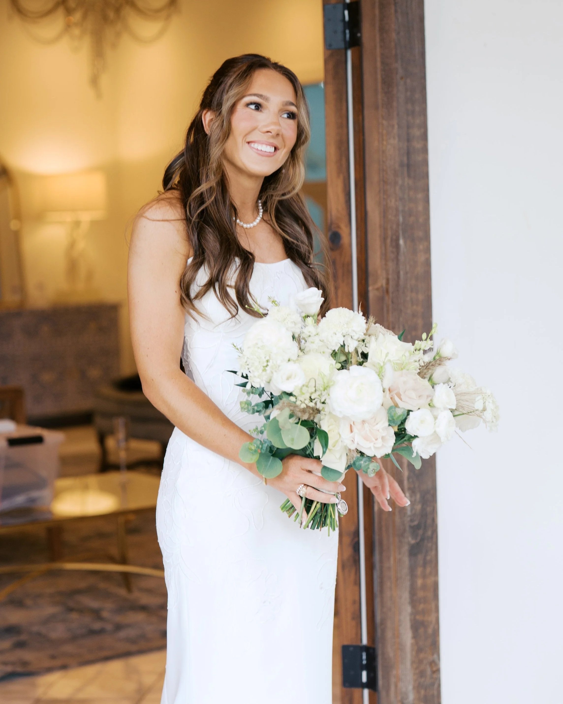 Happy bride in a white wedding dress holding a bouquet of white and blush flowers.