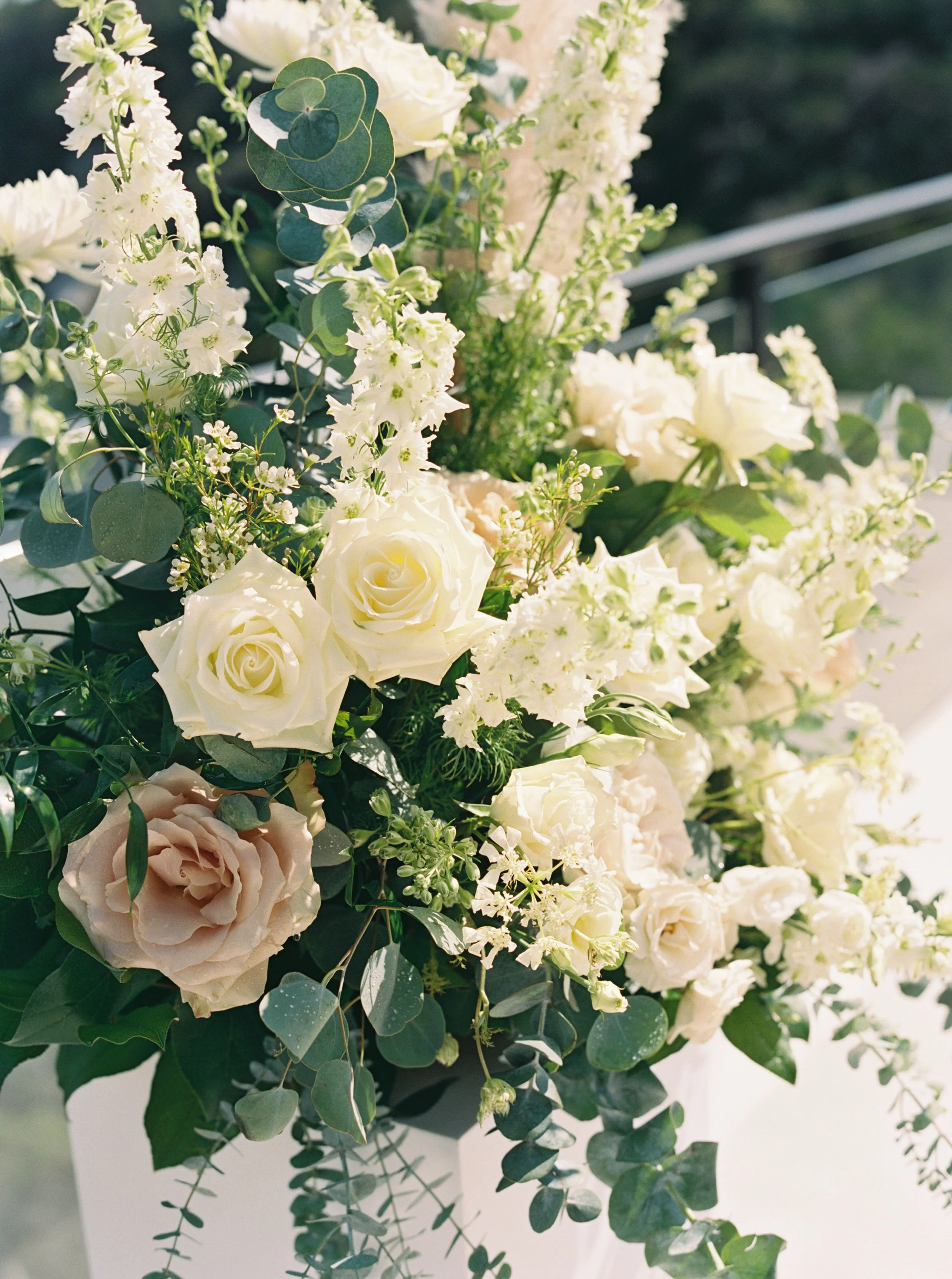 A bouquet of white and cream roses, white hydrangeas, and assorted greenery including eucalyptus leaves.