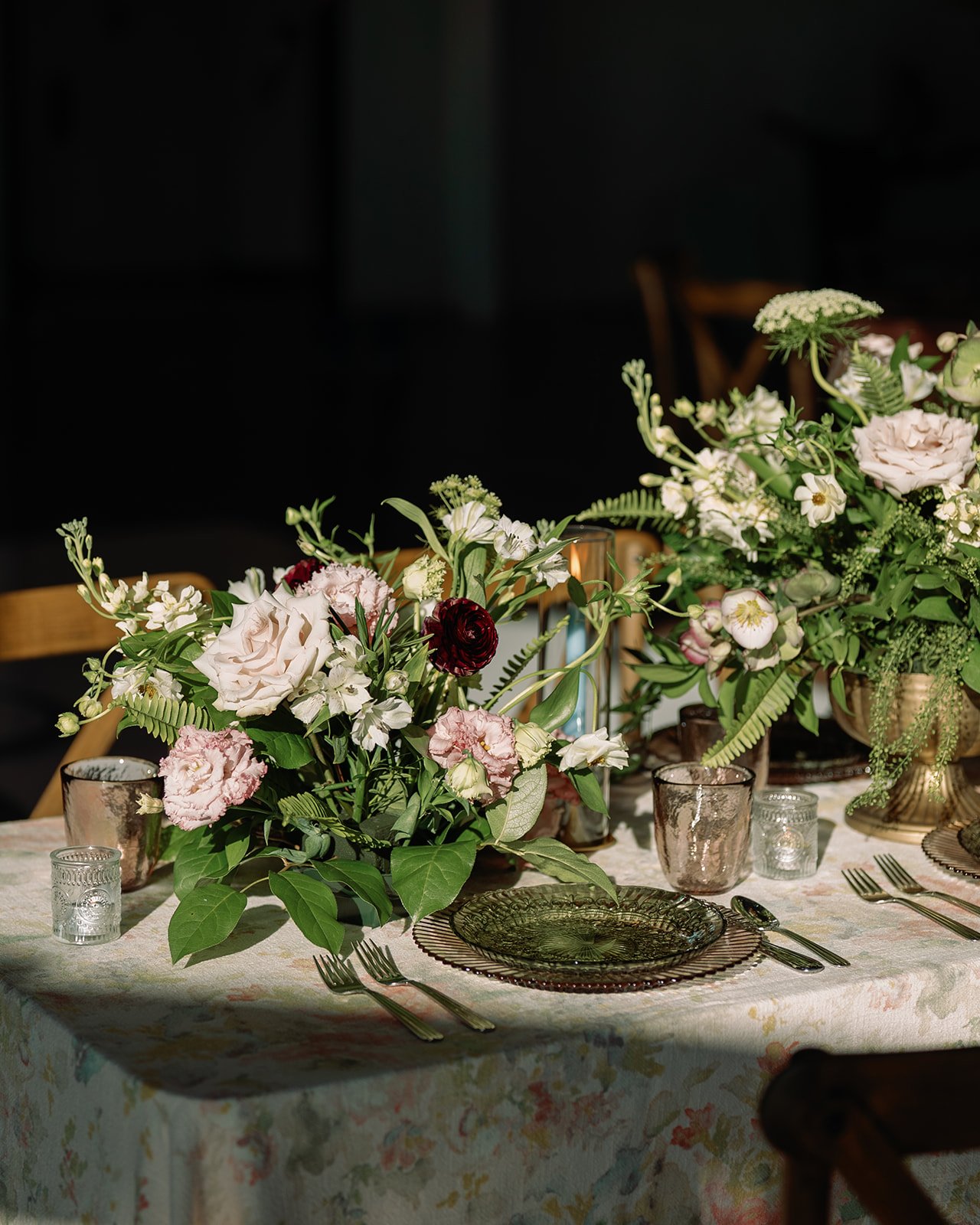 Elegant dining table decorated with pink and white floral arrangements, candles, and glassware.