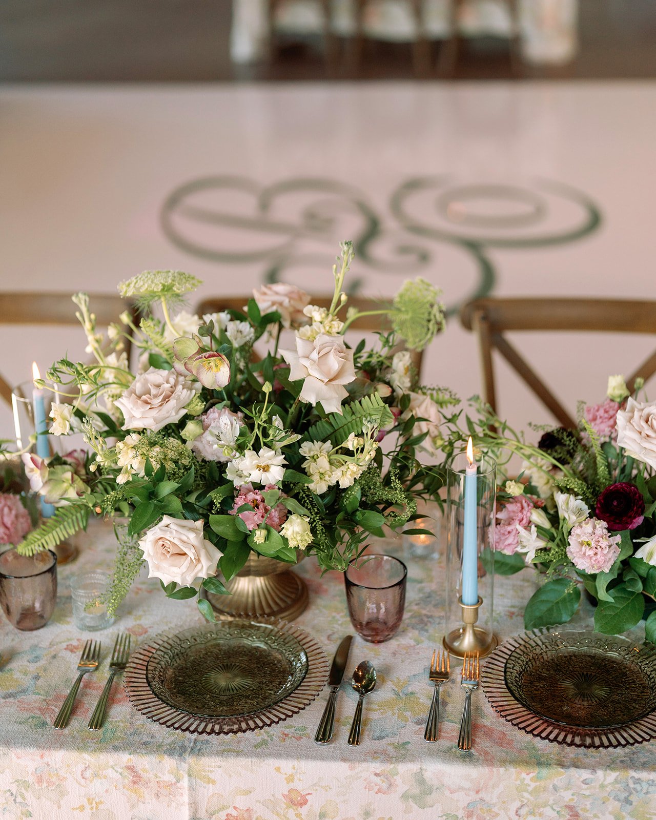 A decorated dining table with floral centerpieces, candle, glassware, and plates set for a meal.