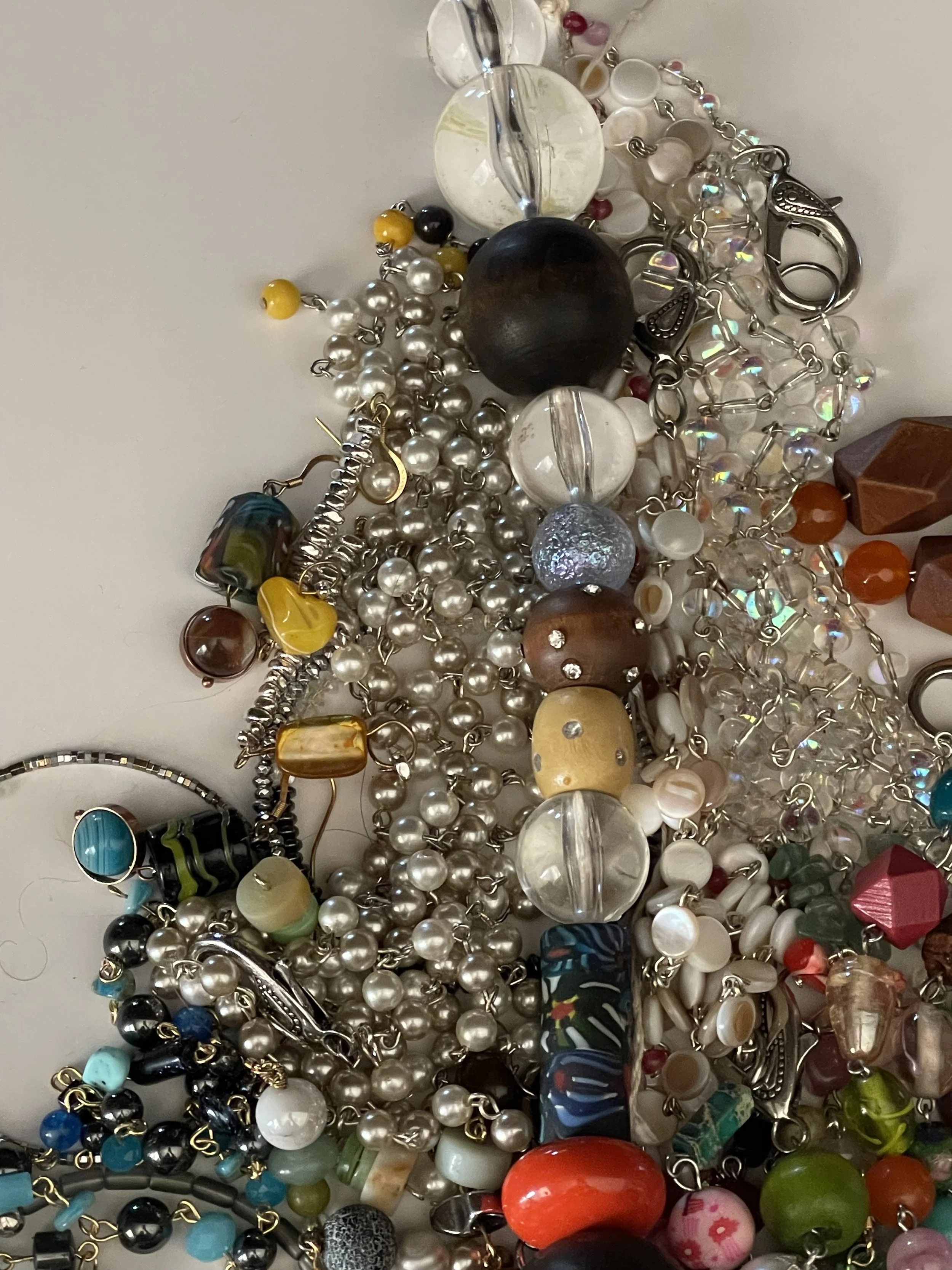 Various colorful beaded jewelry necklaces and bracelets piled together on a surface.