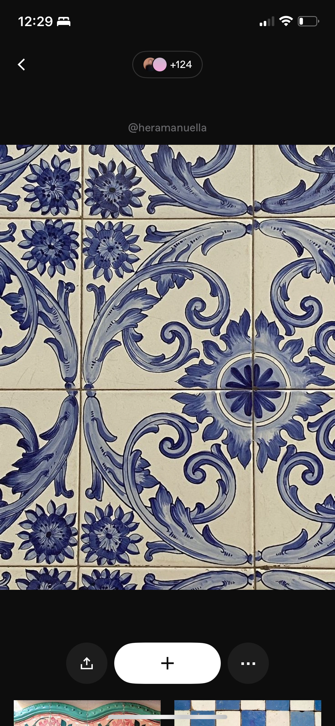 Close-up of decorative blue and white ceramic tile with floral and scroll patterns.