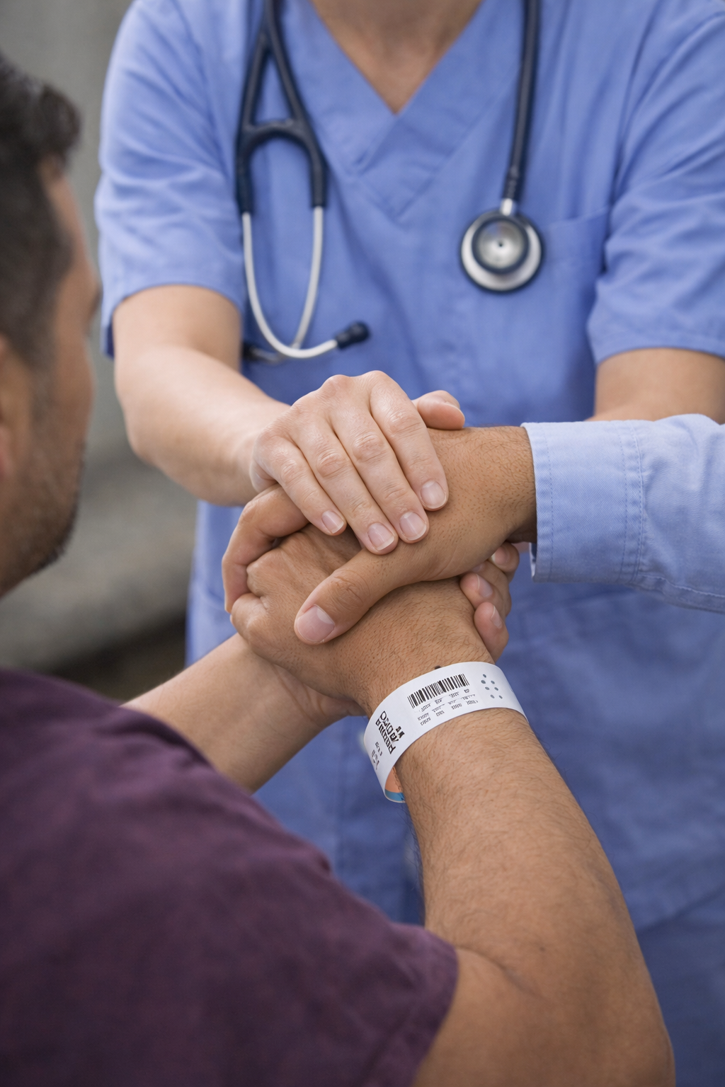 Image of patient holding a doctor and a man's hand