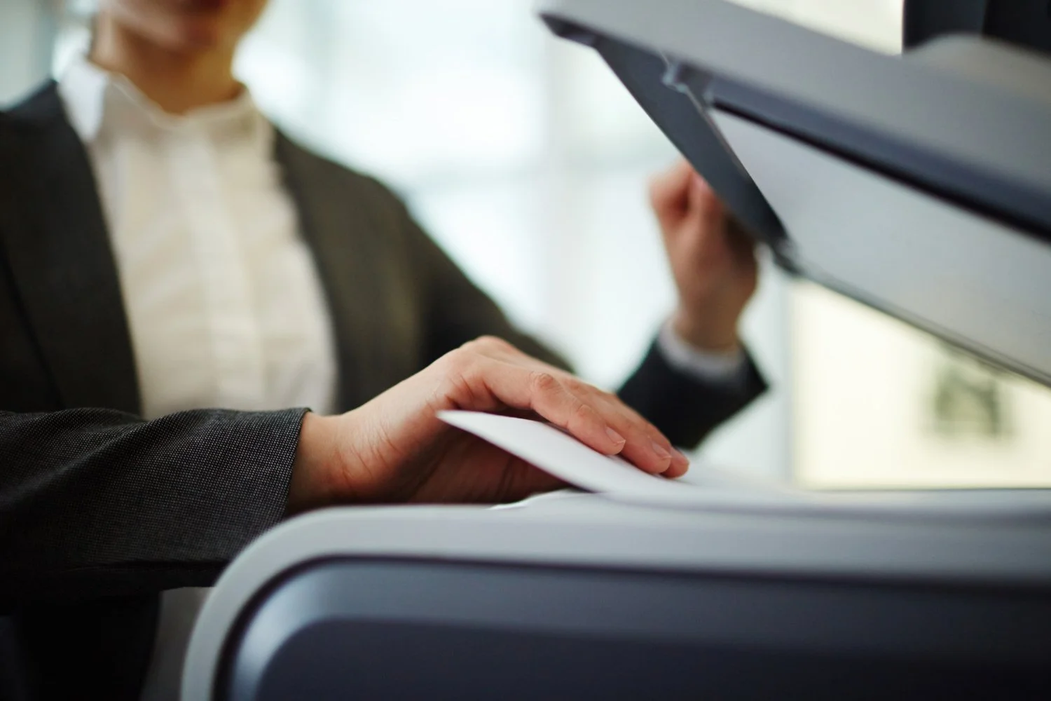 Person printing documents at a copier or printer in a professional setting.