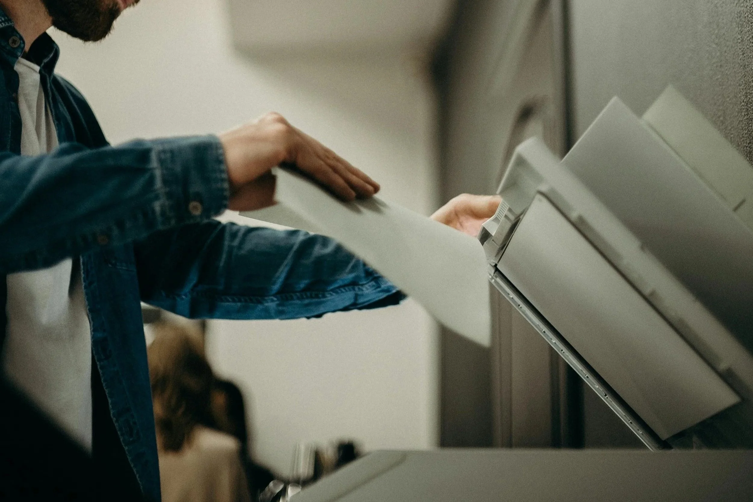 Person in a denim jacket inserting a card into an ATM machine.