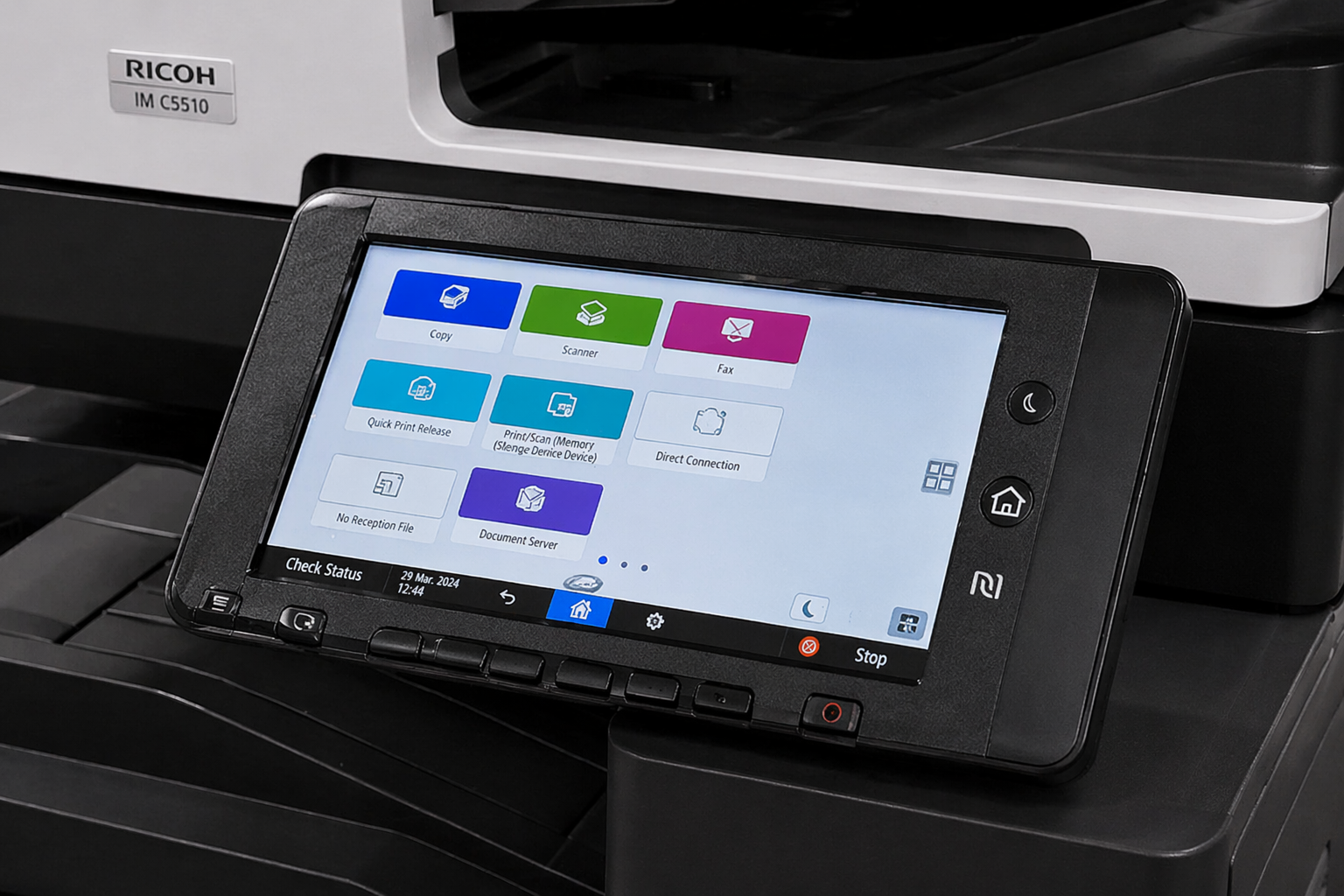 Close-up of a touchscreen control panel used for printing, scanning, faxing, and connecting devices, positioned near a Ricoh multifunction printer.