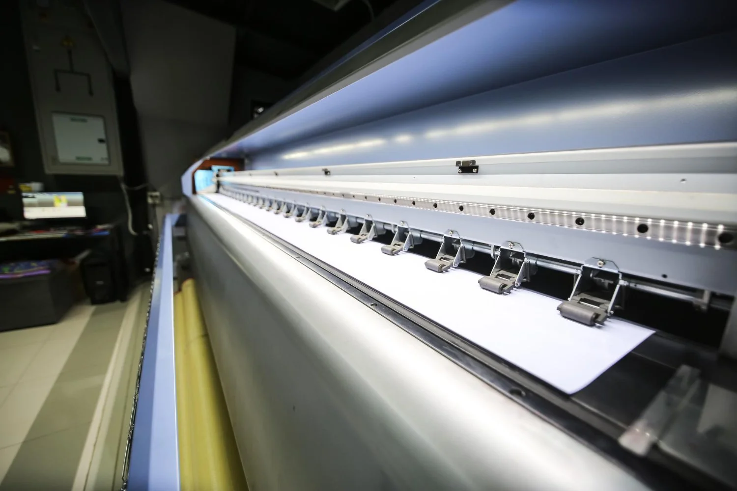 Close-up of a large-format digital printer printing on a wide strip of white paper.