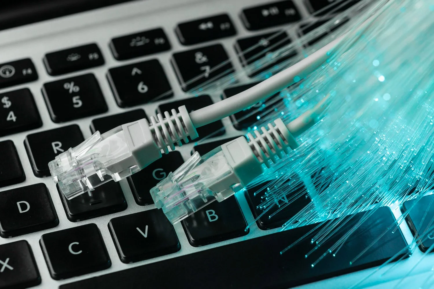 Close-up of Ethernet cables on a computer keyboard with digital light effects.