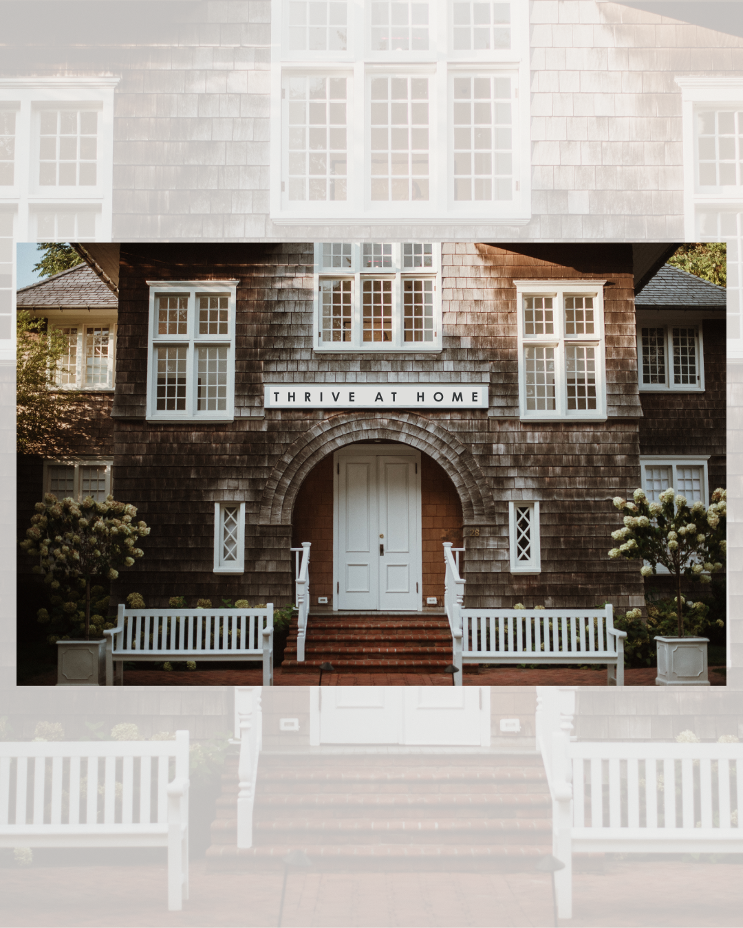 A house with a sign that says "THRIVE AT HOME" above the entrance, featuring a wooden exterior, white-framed windows, a white front door, brick stairs, white benches, and decorative bushes.