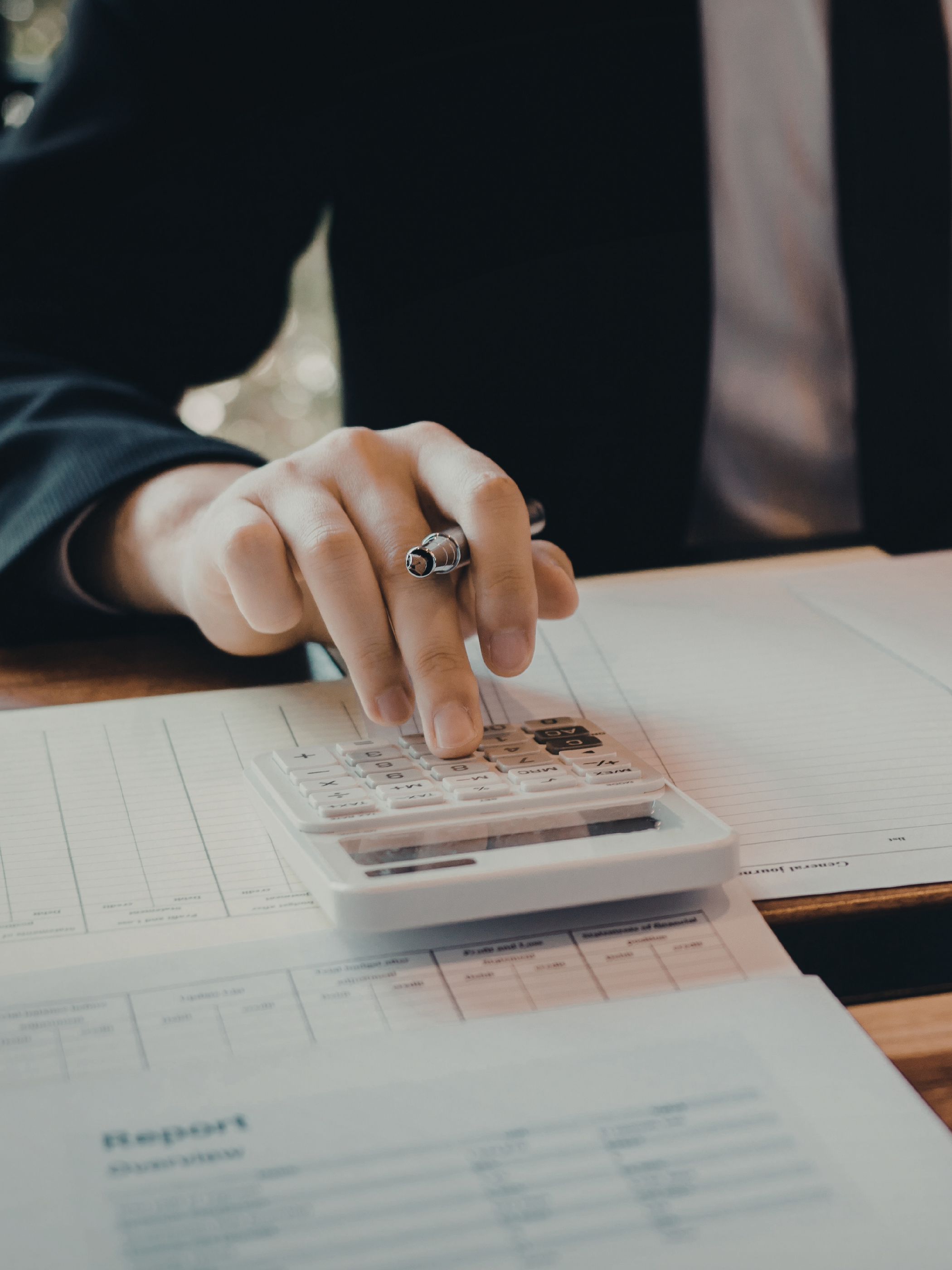 Person using a calculator on a desk with financial documents.