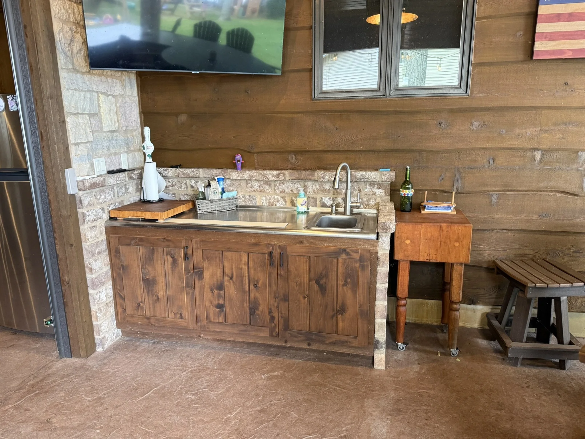 Built-in stainless-steel kitchen workstation, inlaid cutting board, sink, and rustic pine cabinets.