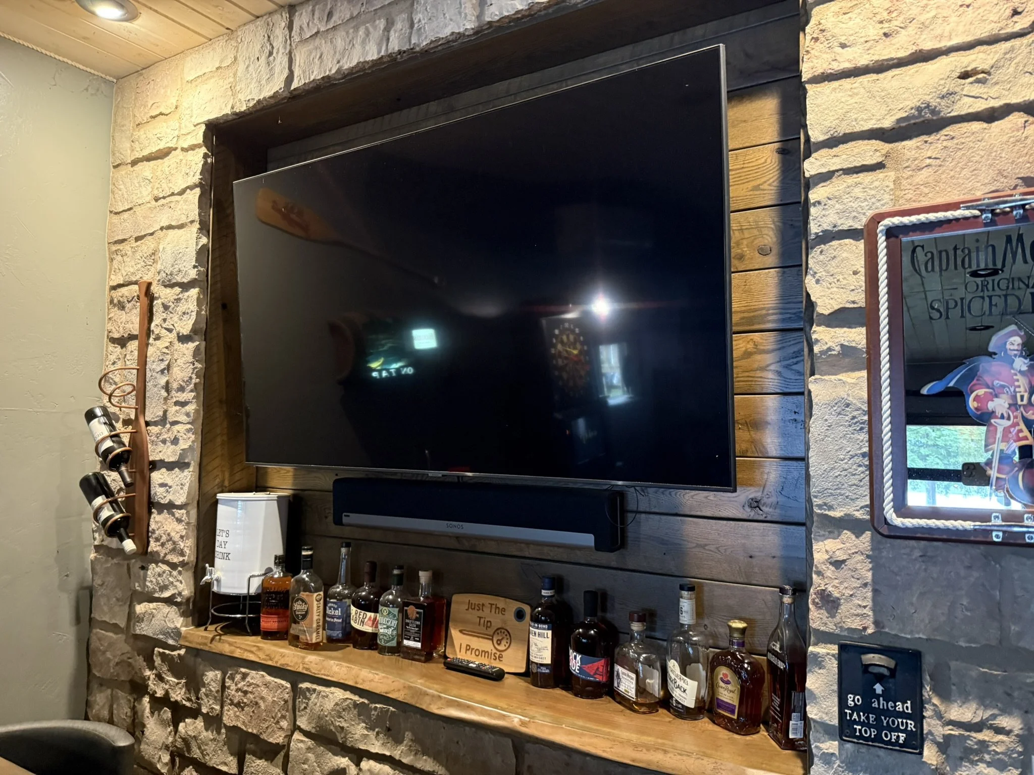 Rustic oak wall recess for tv, black cherry live edge shelf, and flag stone wall