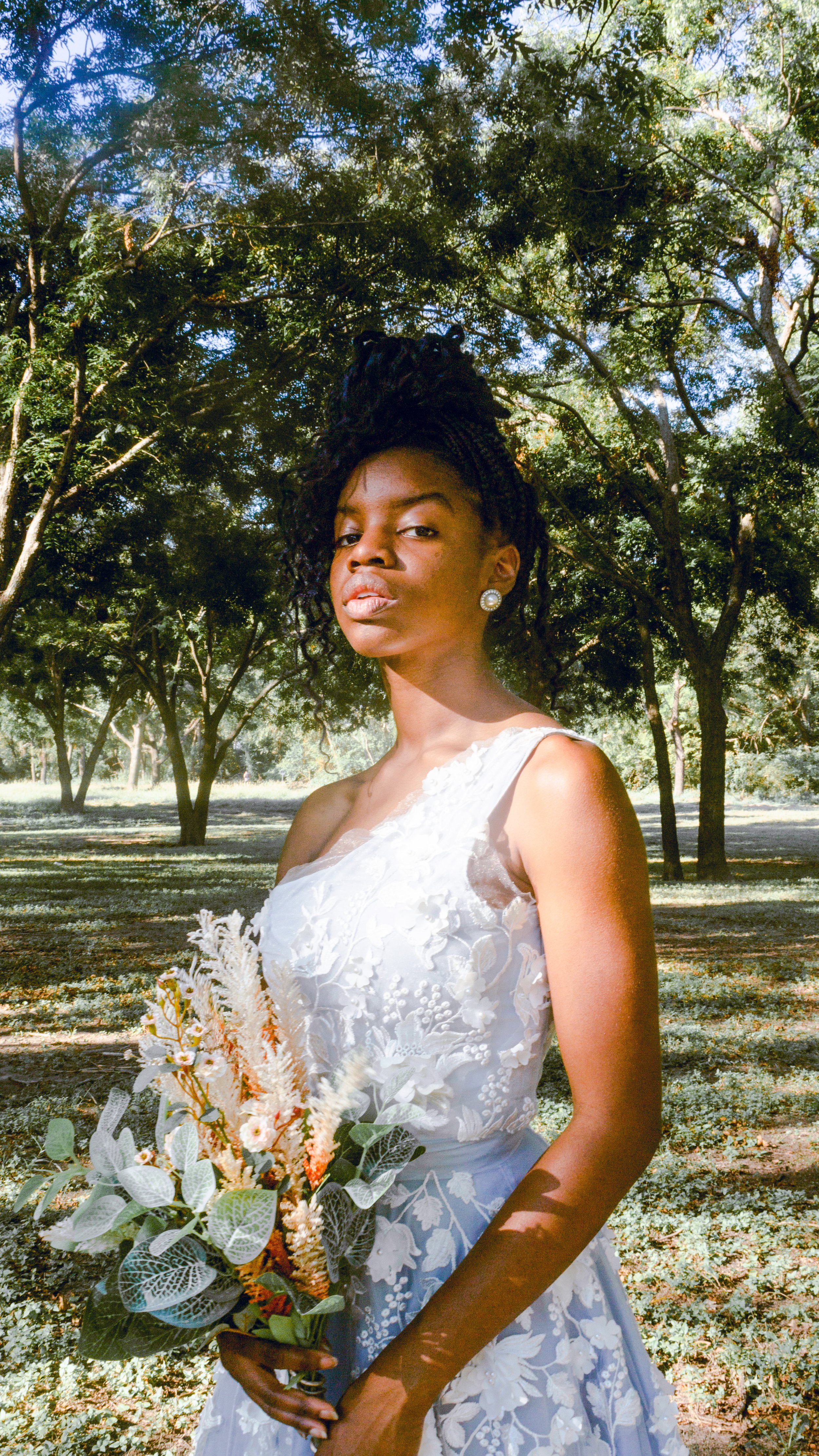 woman in park wearing a floral wedding gown holding a bouquet of flowers