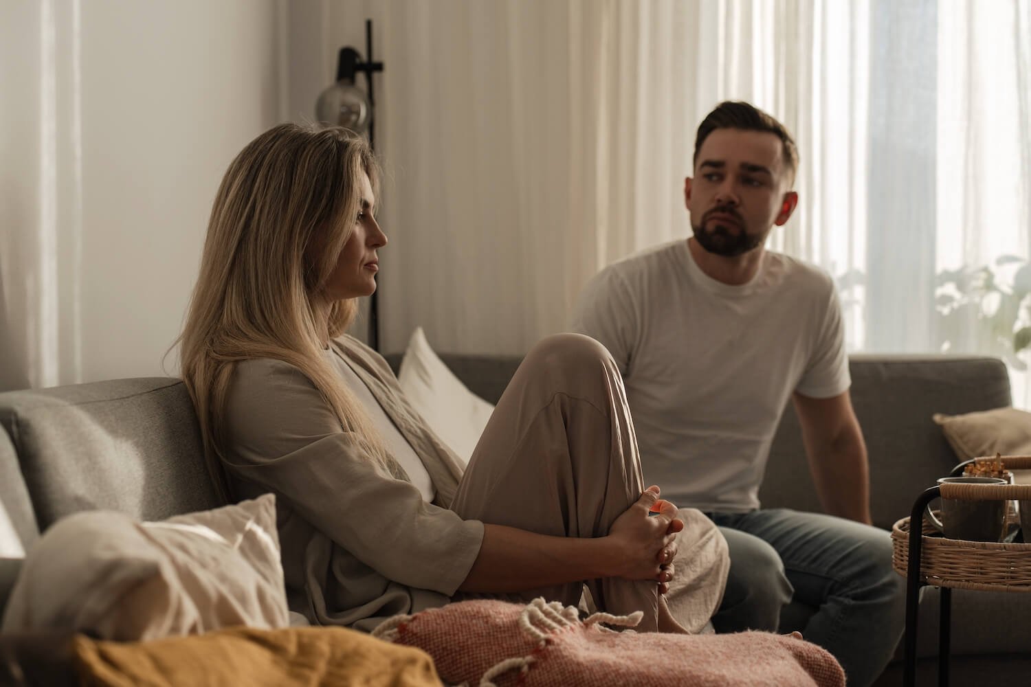 Couple sitting apart with visible emotional distance and tension in a relationship