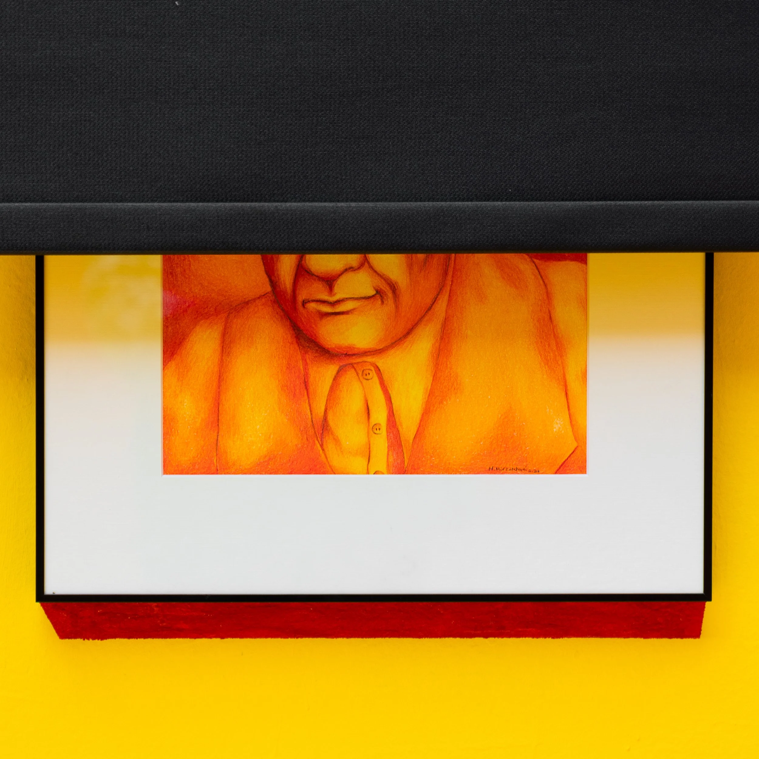 A framed artwork of an orange-toned portrait of a person's face and upper body against a yellow background, mounted on a yellow wall.