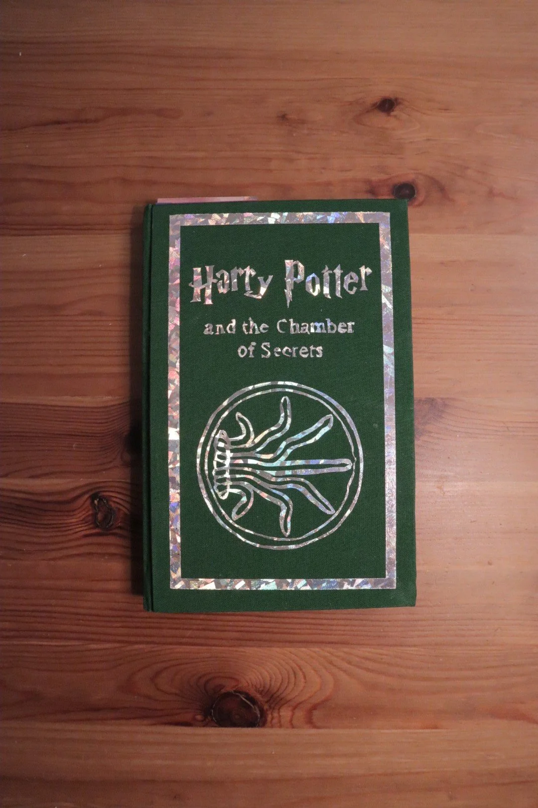 Cover of the book 'Harry Potter and the Chamber of Secrets' placed on a wooden surface.