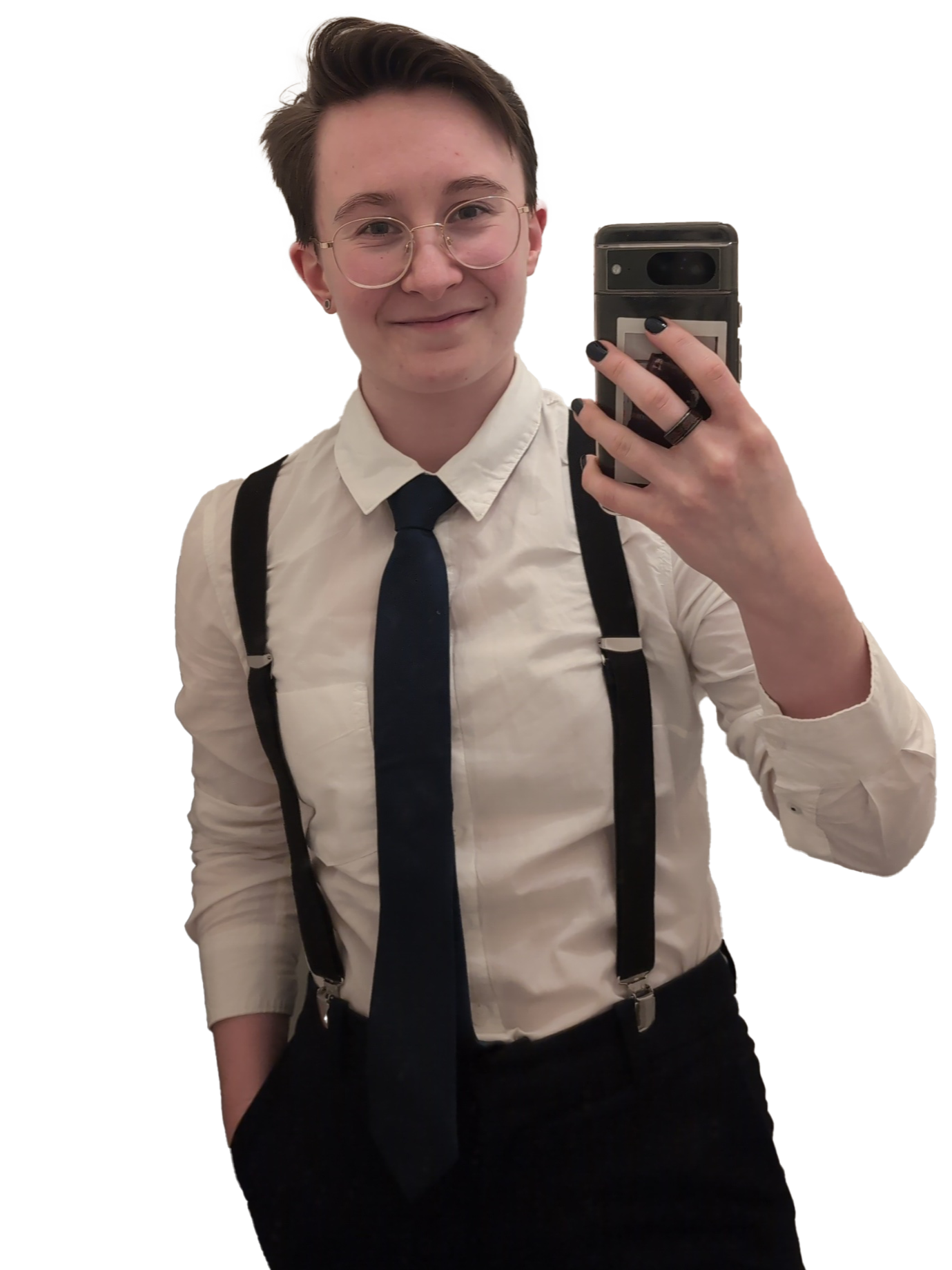 Young person with short hair and glasses taking a mirror selfie, wearing a white shirt, dark tie, suspenders, and black pants.