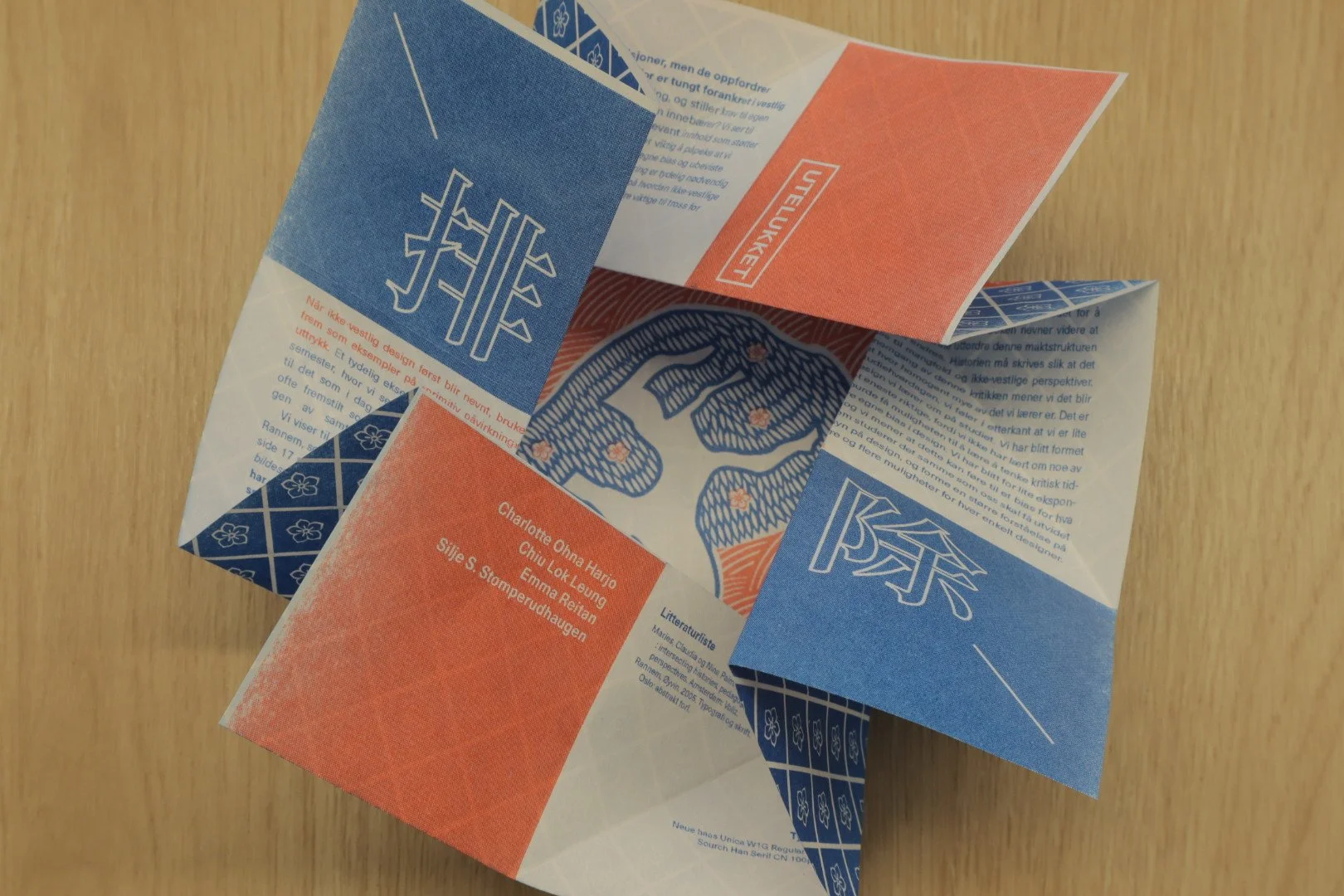 Folded paper palette with orange, blue, and white sections, featuring Asian characters, floral patterns, and author names in English.