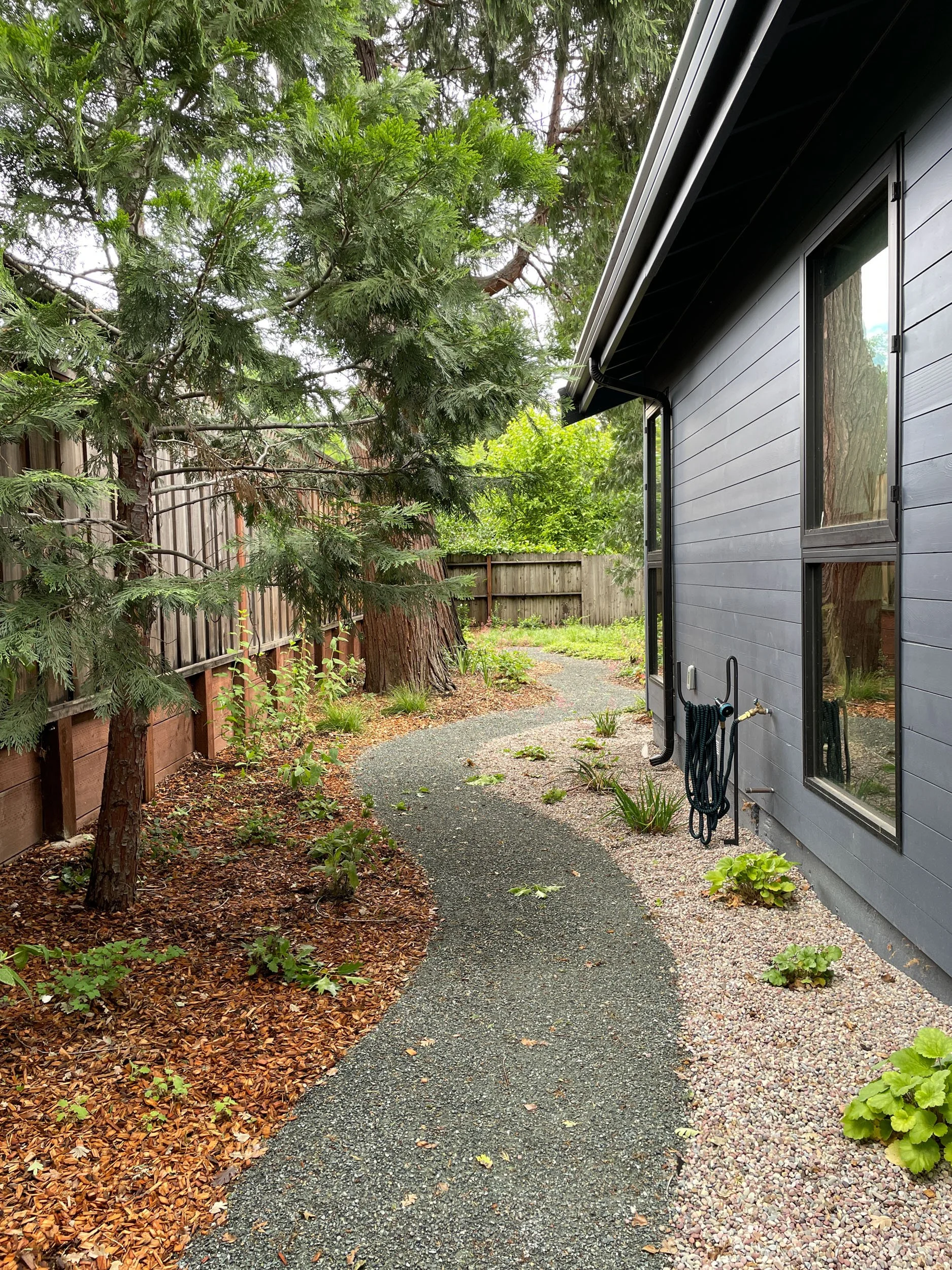 A gravel pathway with 5 feet of space from house to garden in zone 0 gravel mulch along house california native plants