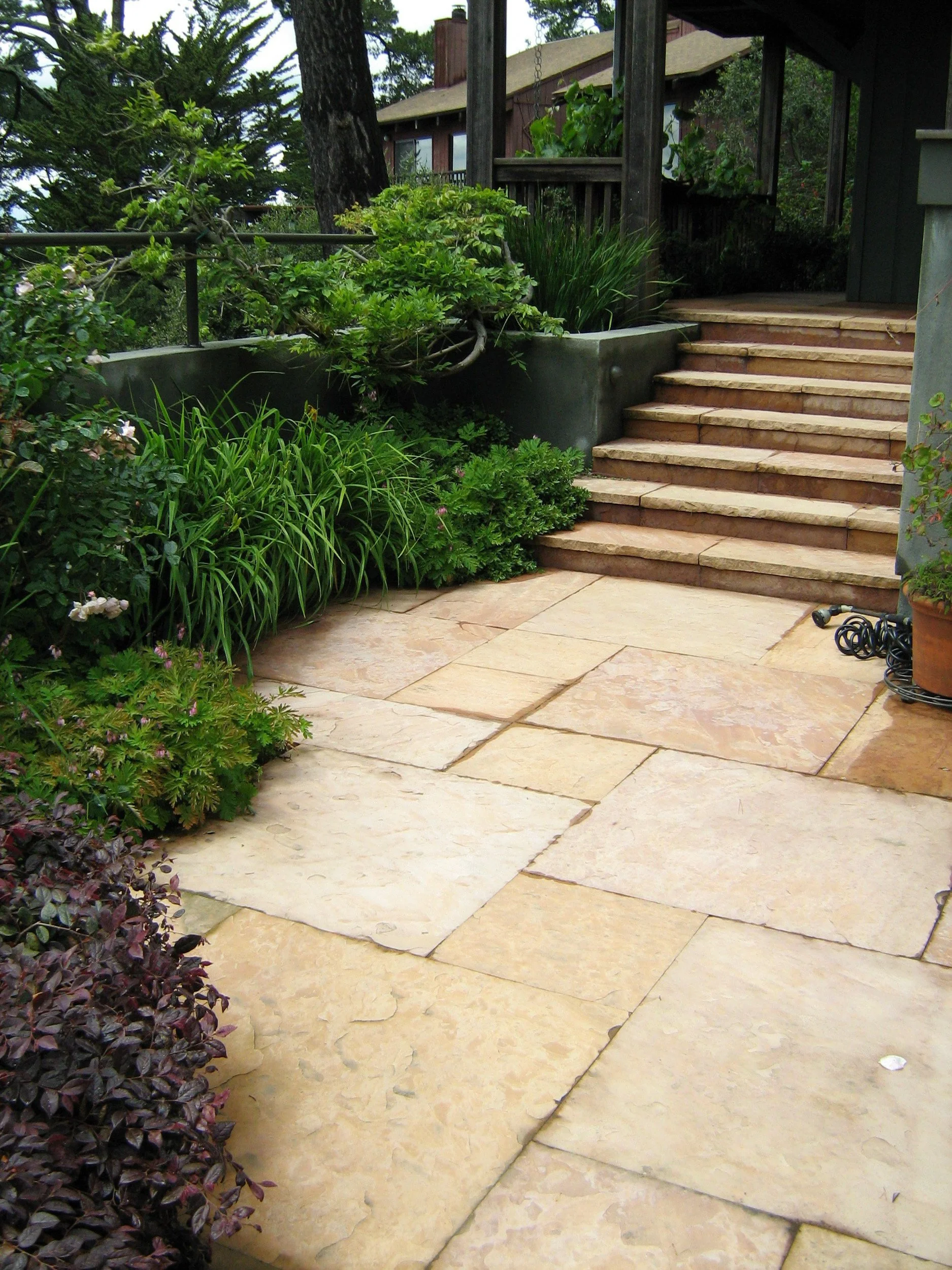 A tan geometric paver stone patio and stone steps.