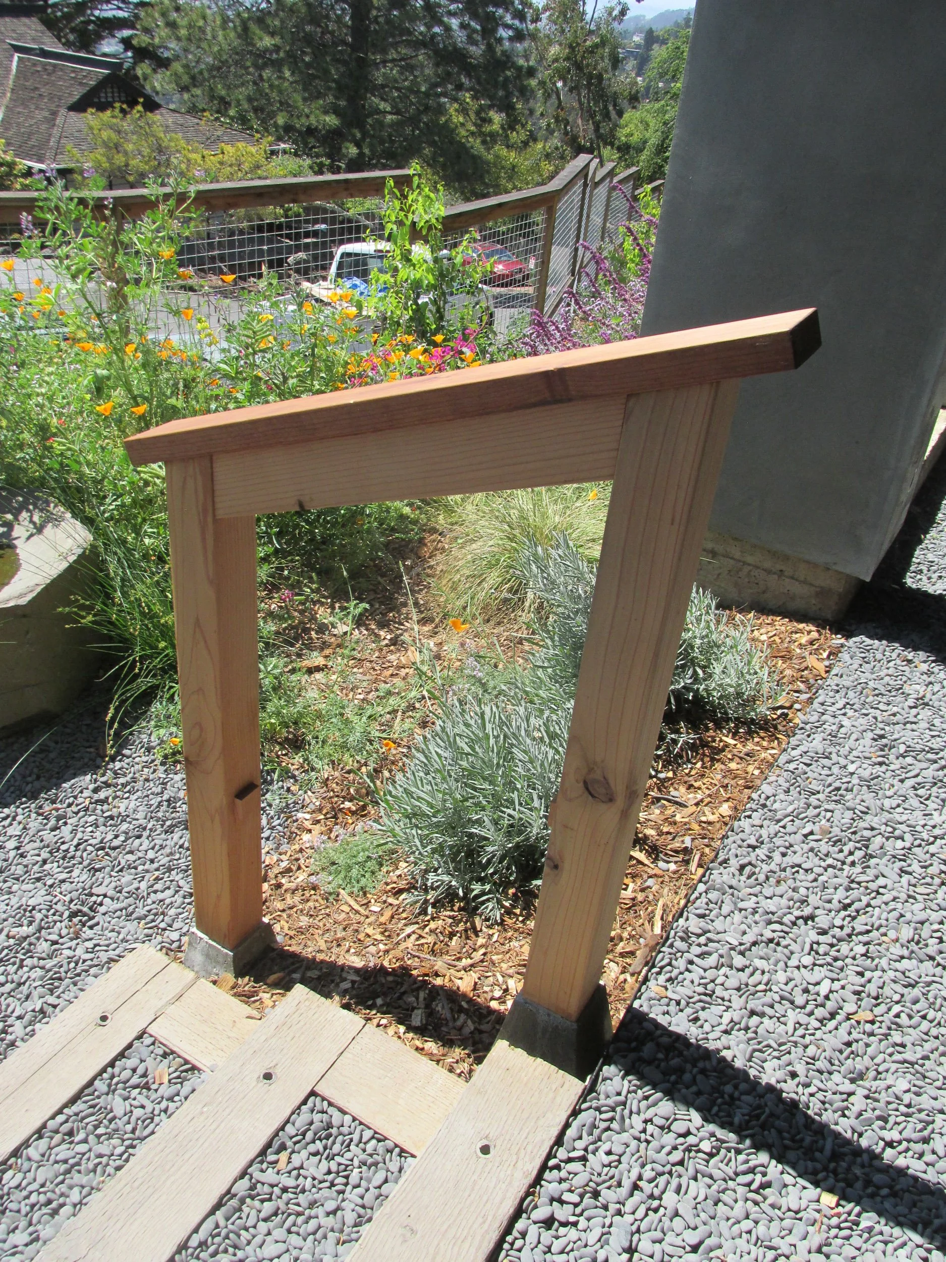 Wood railing next to timber tie steps with grey gravel pathway